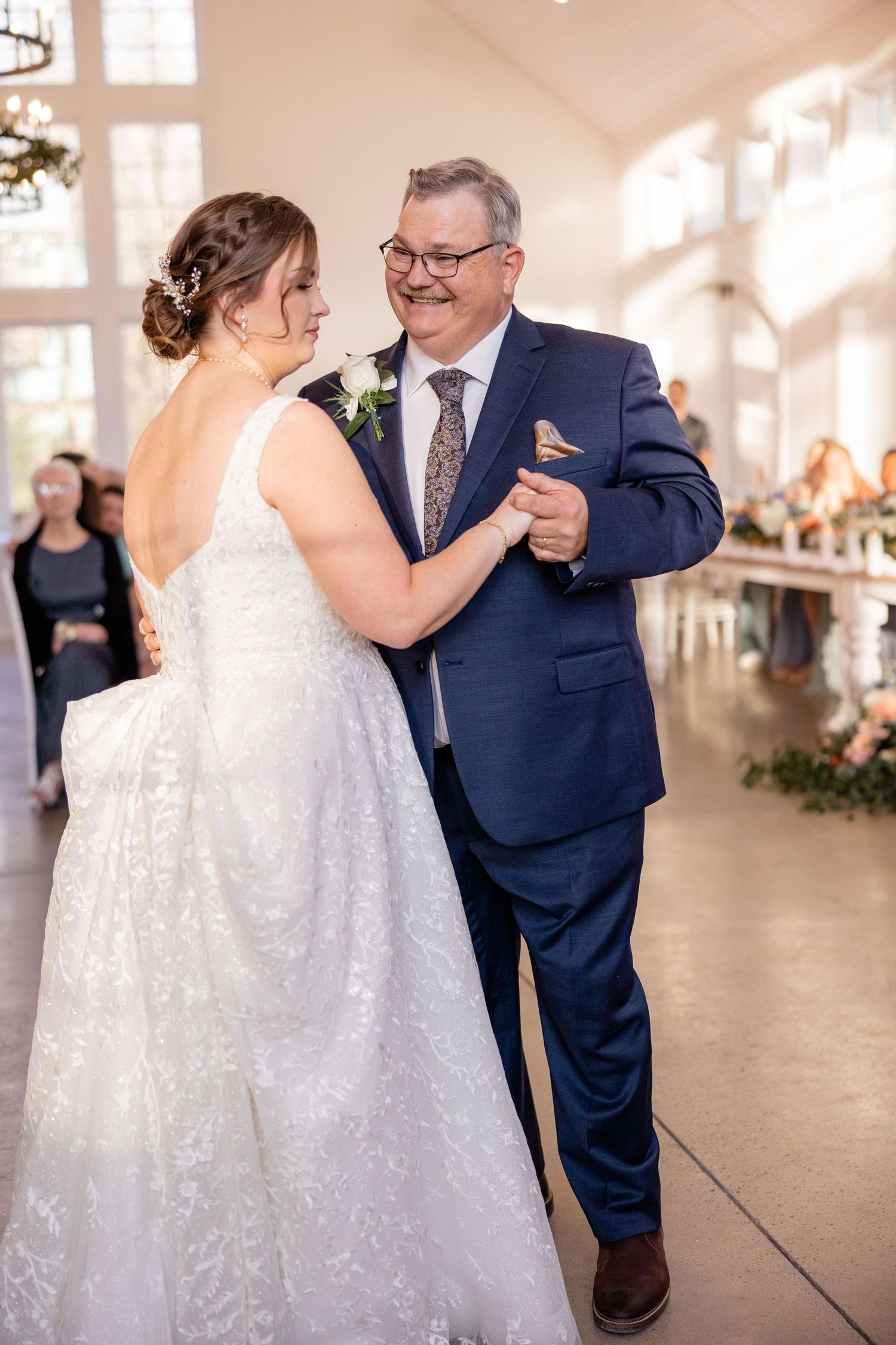 Emotional dance moment in a sunlit chapel interior with elegant white dress and navy suit.