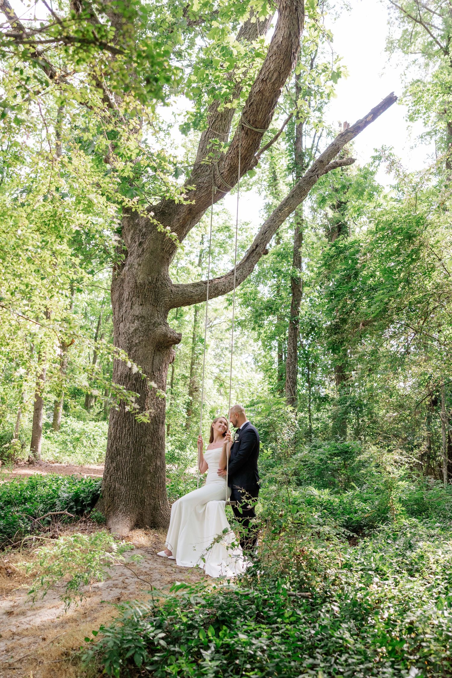 A romantic wedding photo shoot in a wooded area with natural lighting.