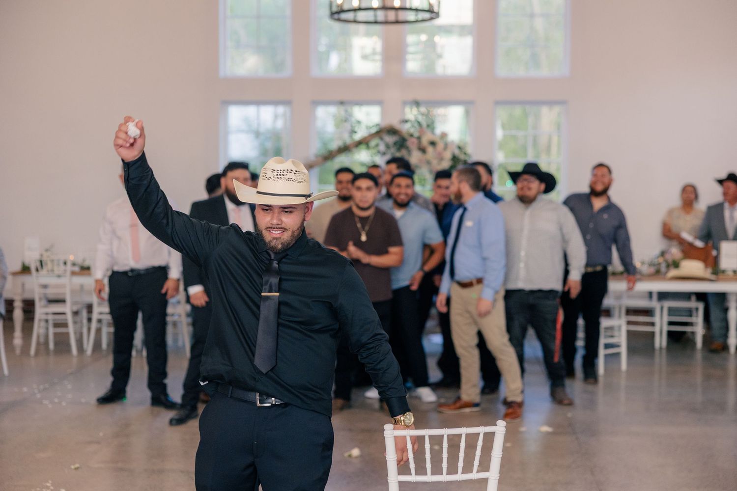 Wedding reception venue features elegant white chairs and tables set up for celebration indoors.