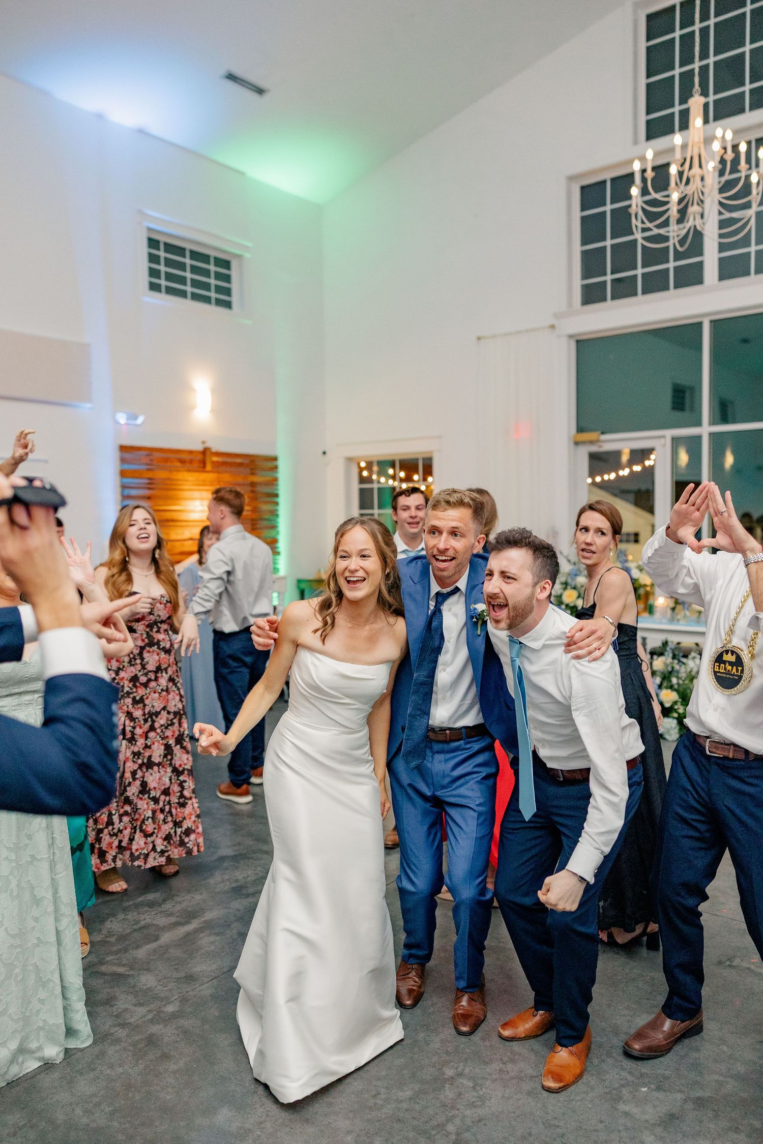 Bride and groom celebrate joyfully with guests on the dance floor at wedding reception.