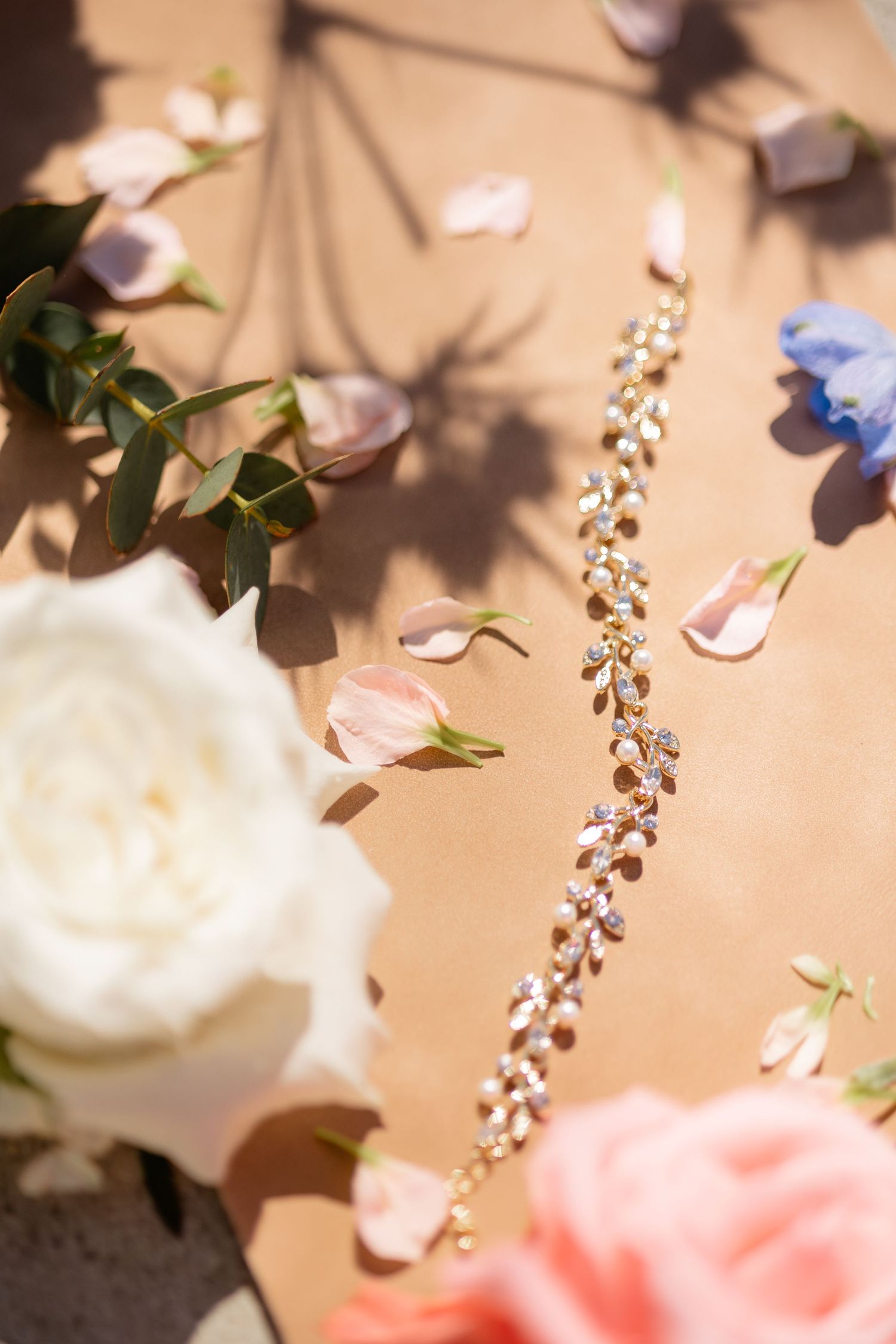 Delicate pink and white flower petals with crystal beaded accessories arranged against a soft beige background.