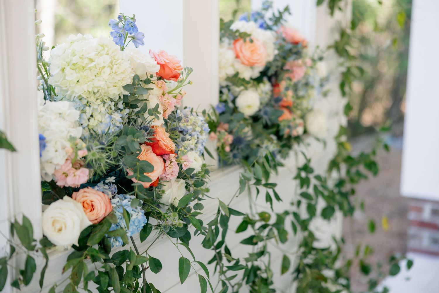 Elegant floral arrangements featuring blue and peach blooms decorate a bright white space.
