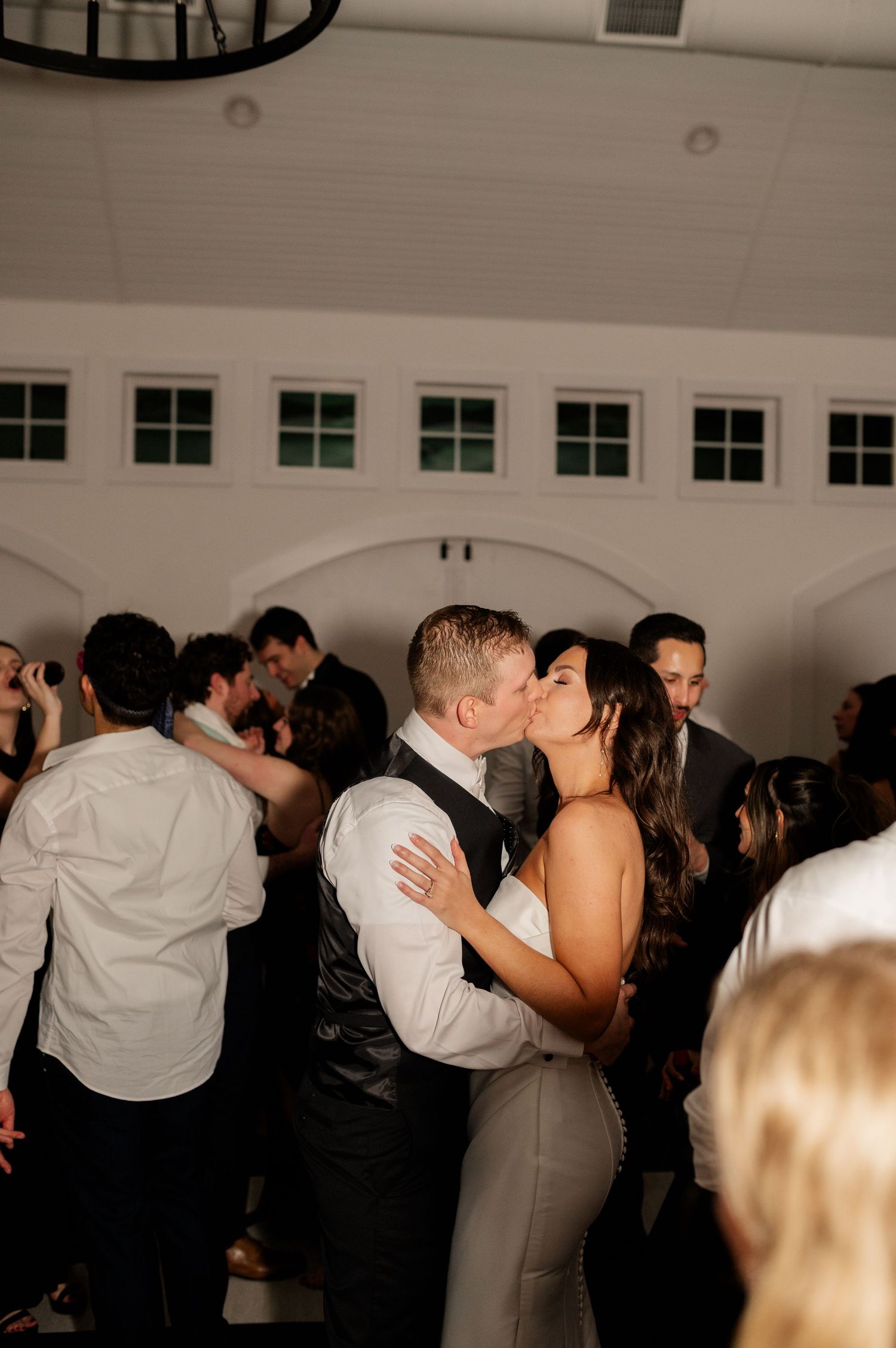 Wedding reception dance floor filled with couples celebrating in dim romantic lighting.