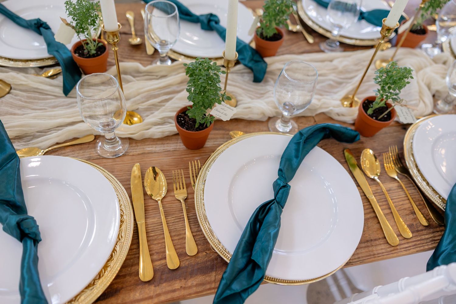 Rustic wedding table settings with teal accents and gold flatware.