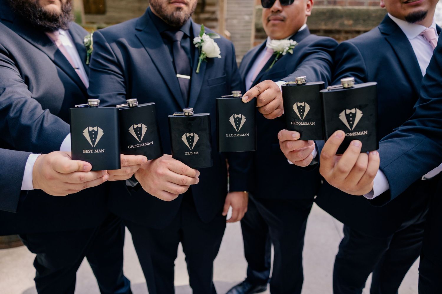 Row of groomsmen holding black boxes against dark formal attire.