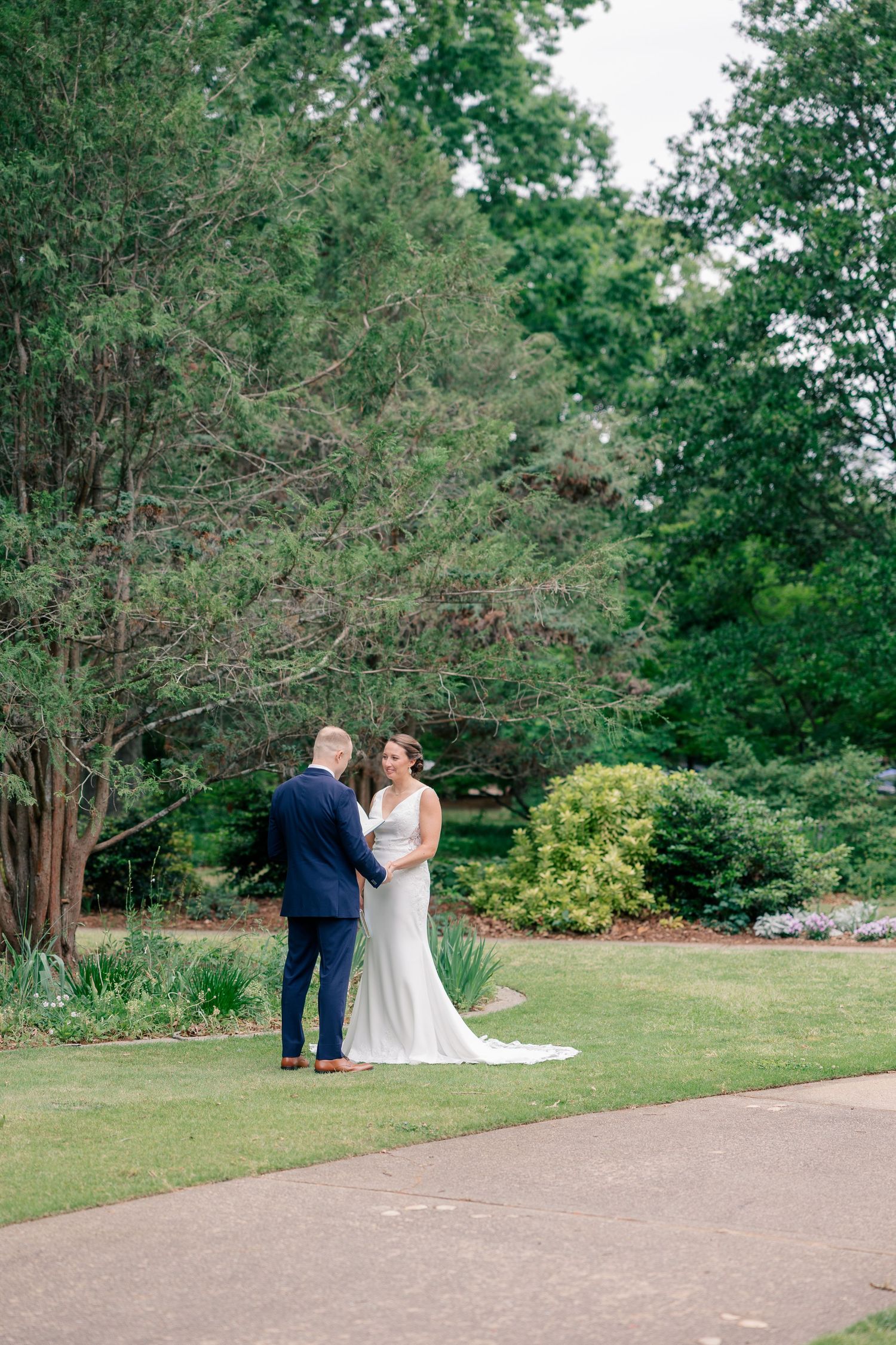 Bride and groom share a tender first look moment in a lush green garden on their wedding day.