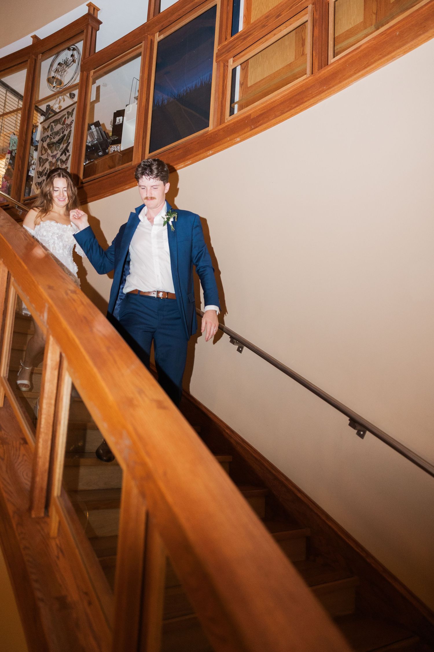 Wooden staircase with warm lighting and wooden railings in an interior setting.
