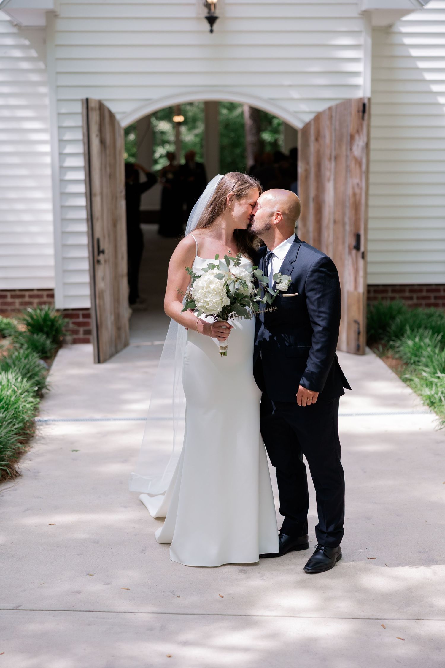 Intimate first look moment between couple on white columned porch of vintage building.