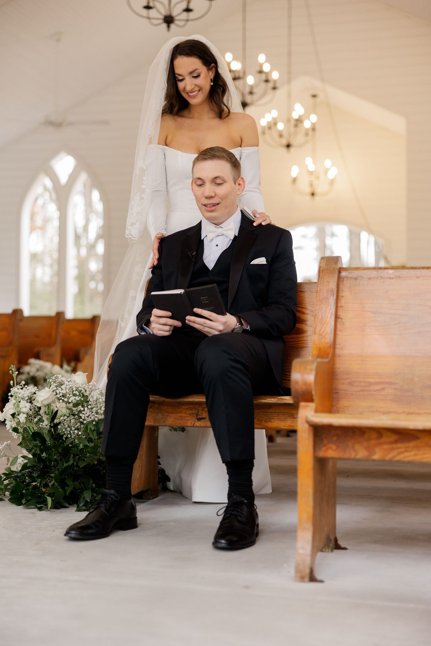Couple shares intimate moment reading device together in church setting with chandeliers.