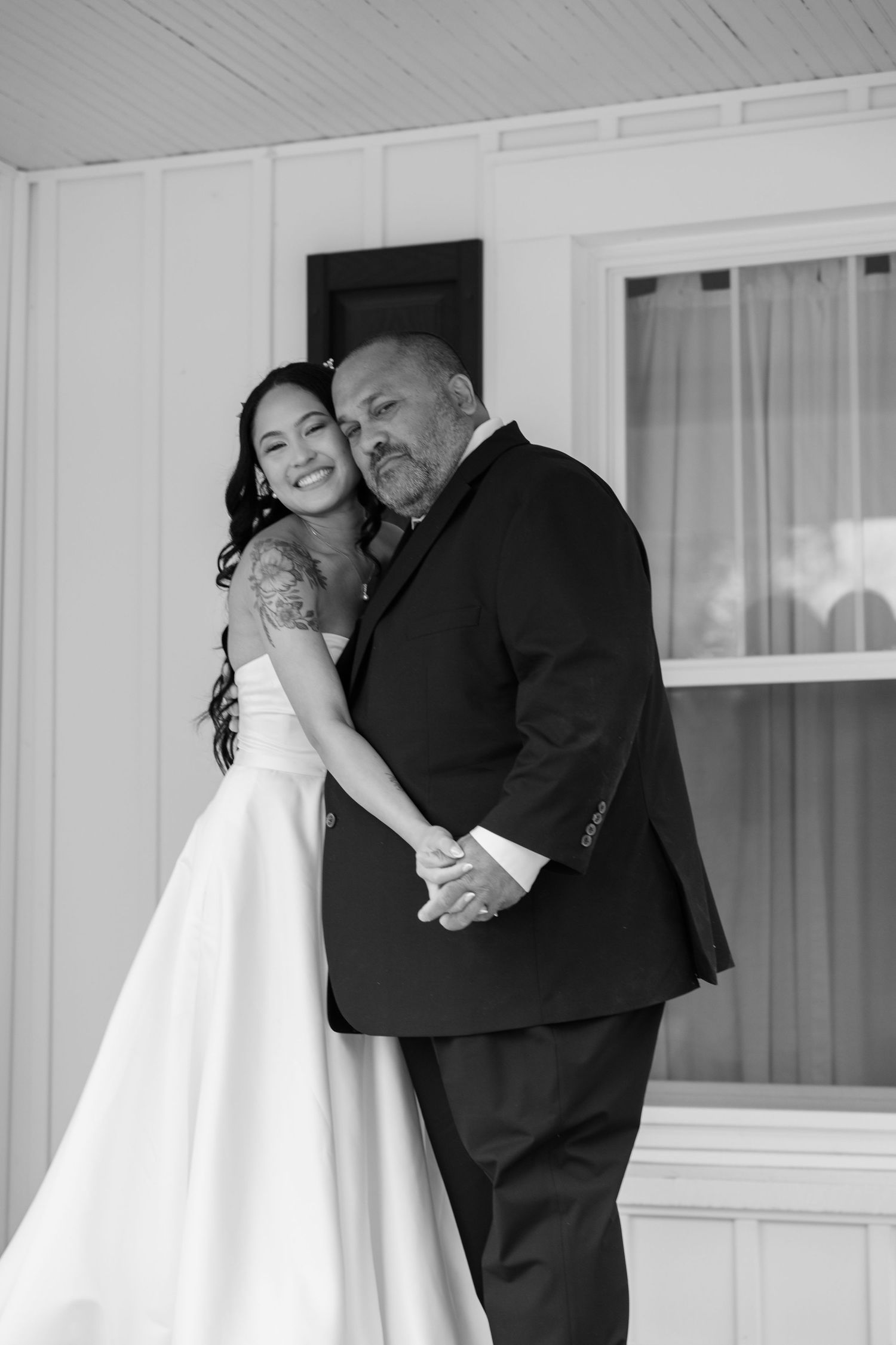 Sweet emotional moments captured during wedding day preparations outside white building.