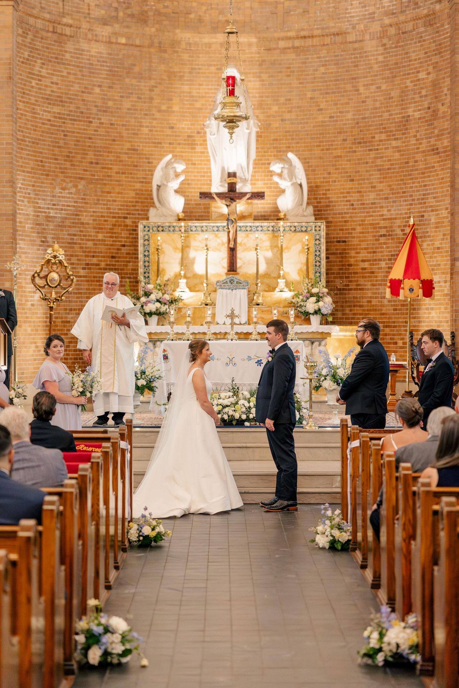 Bride and groom exchange vows at ornate brick church altar during wedding ceremony.