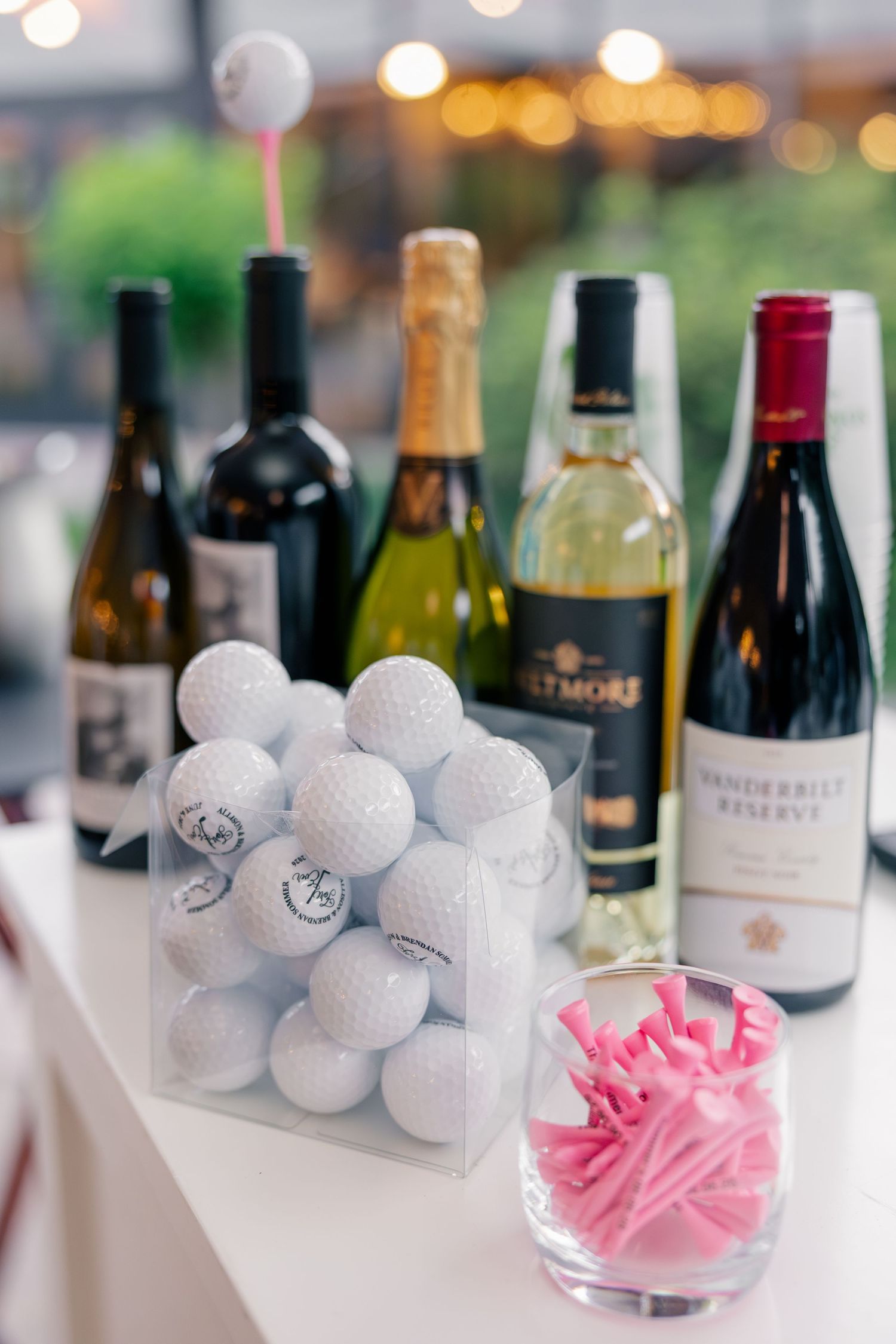 Wedding display featuring monogrammed golf balls, pink tees, and wine bottles as creative reception decor.