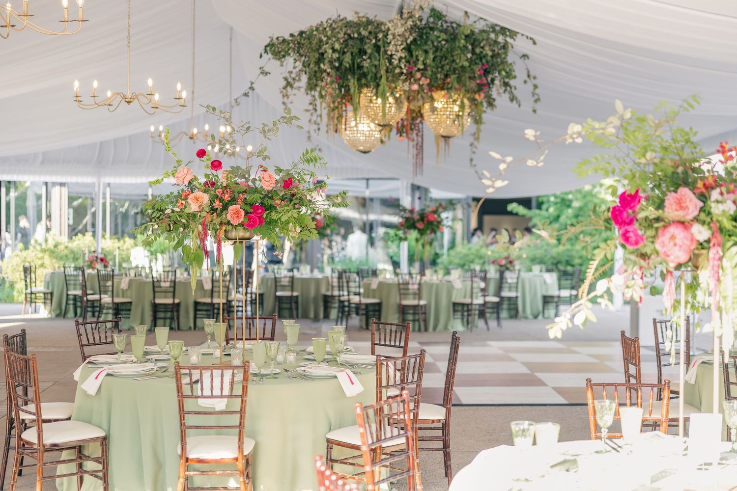 Elegant tented reception with sage green linens, chiavari chairs, and lush floral centerpieces.