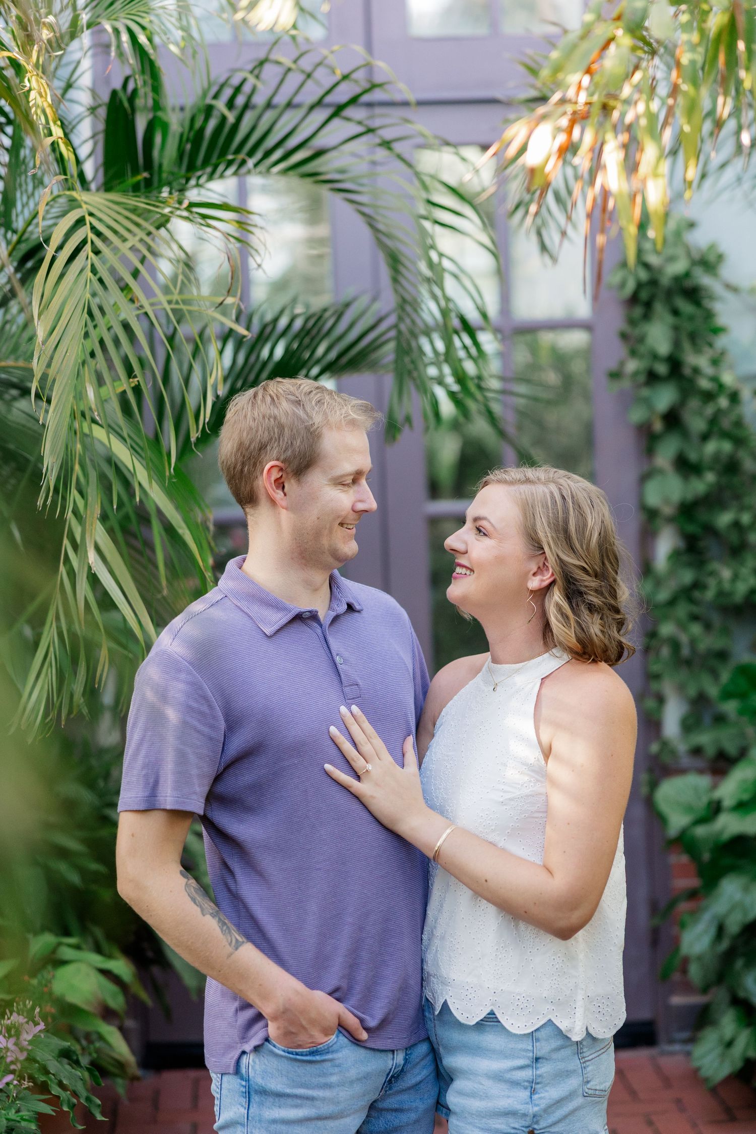 A couple shares joyful laughter among tropical plants and palm fronds.
