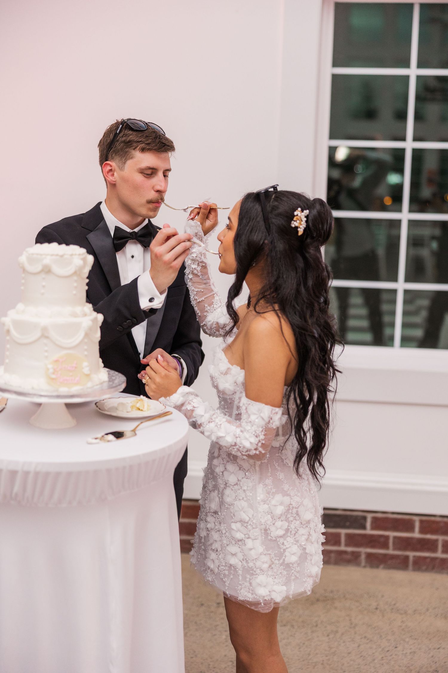 A couple cuts their elegant white wedding cake together during their reception.