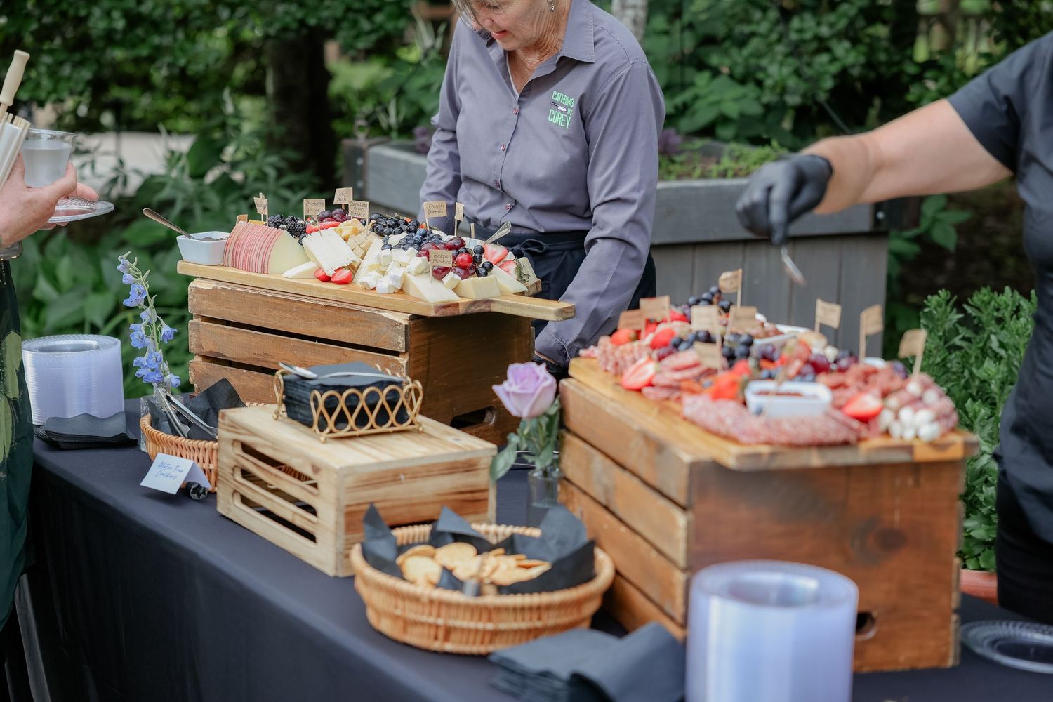 Wooden crates display an array of appetizers and desserts at an outdoor catering setup.