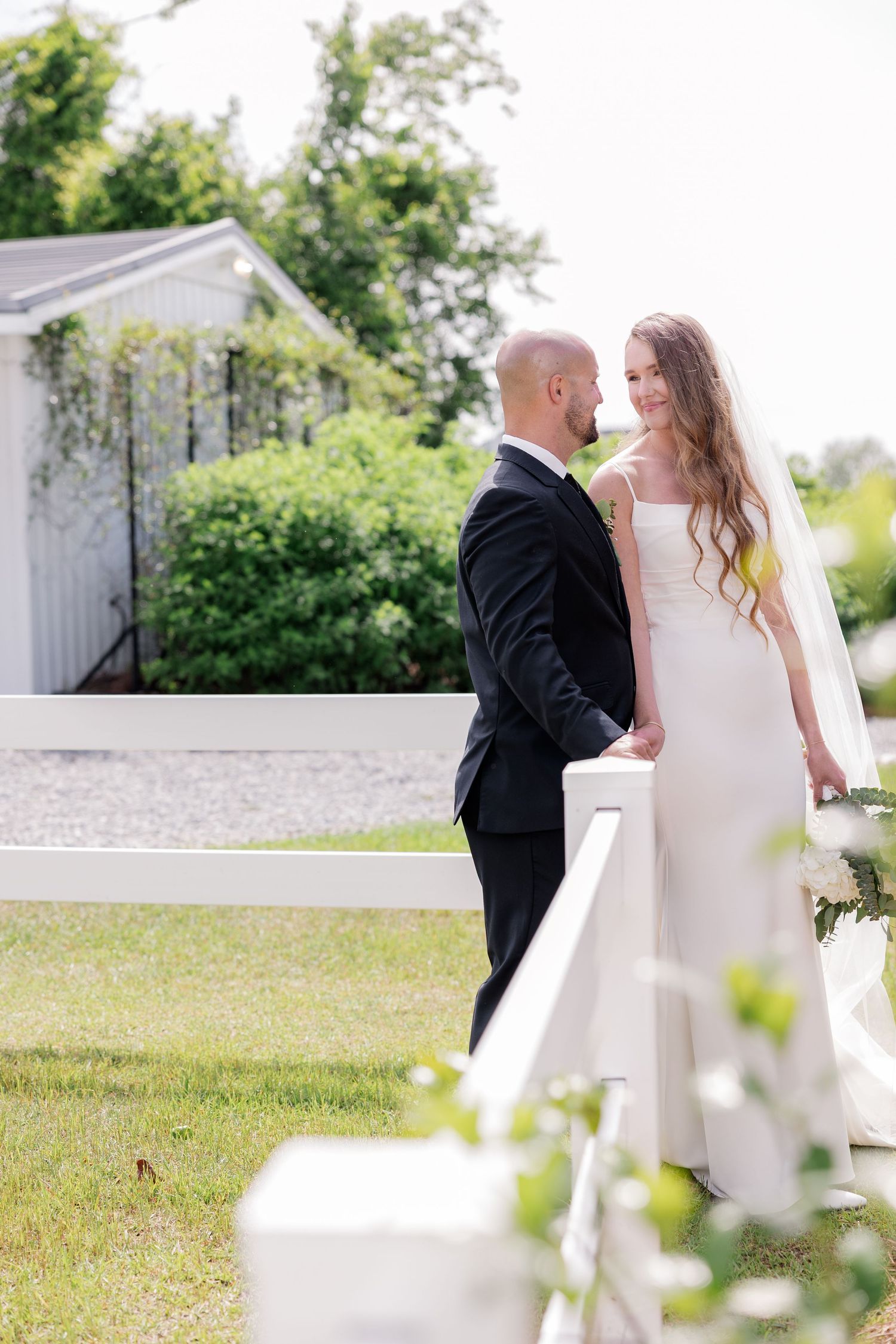 Couple sharing tender moment on white benches in garden setting.