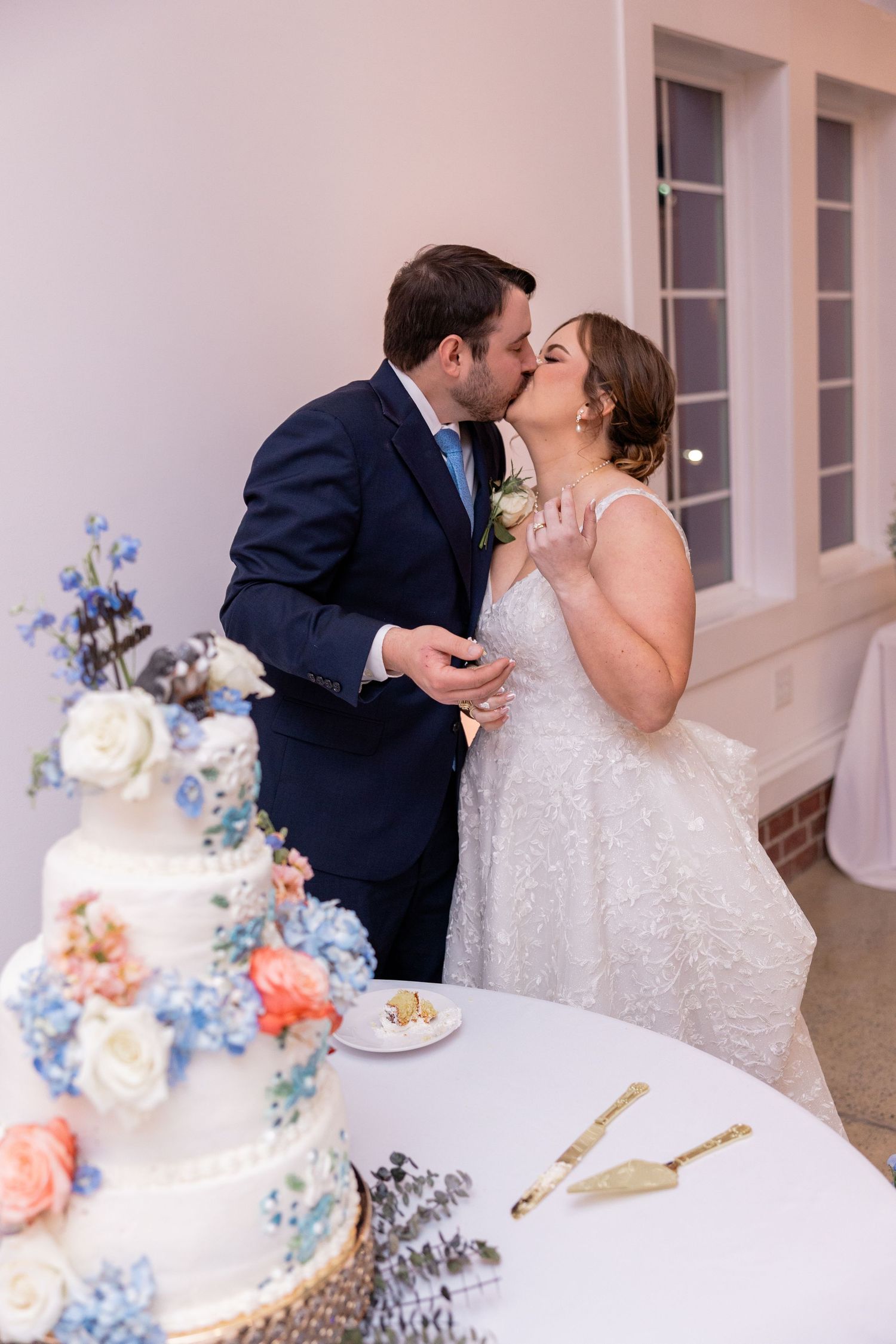 Wedding cake cutting scene with elegant floral decorations in blue and coral tones.