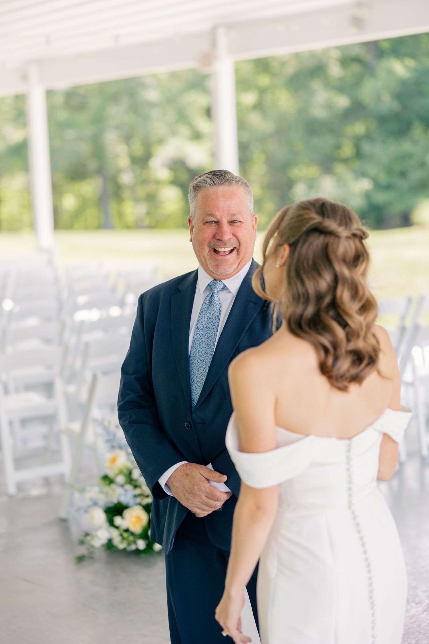 Emotional father smiling at his bride daughter during a first look at an outdoor wedding venue.