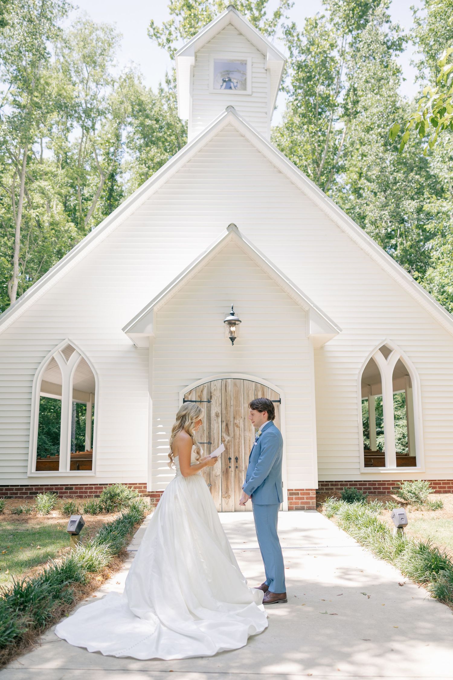 Bride and groom sharing first look outside charming white chapel wedding venue.