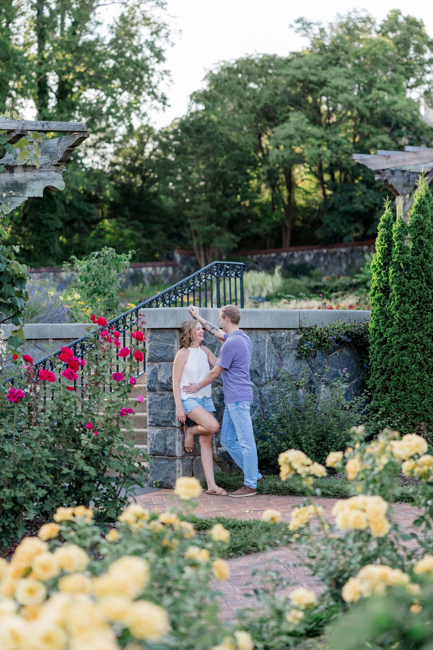 A romantic moment captured in a garden with blooming pink and yellow flowers on a summer evening.