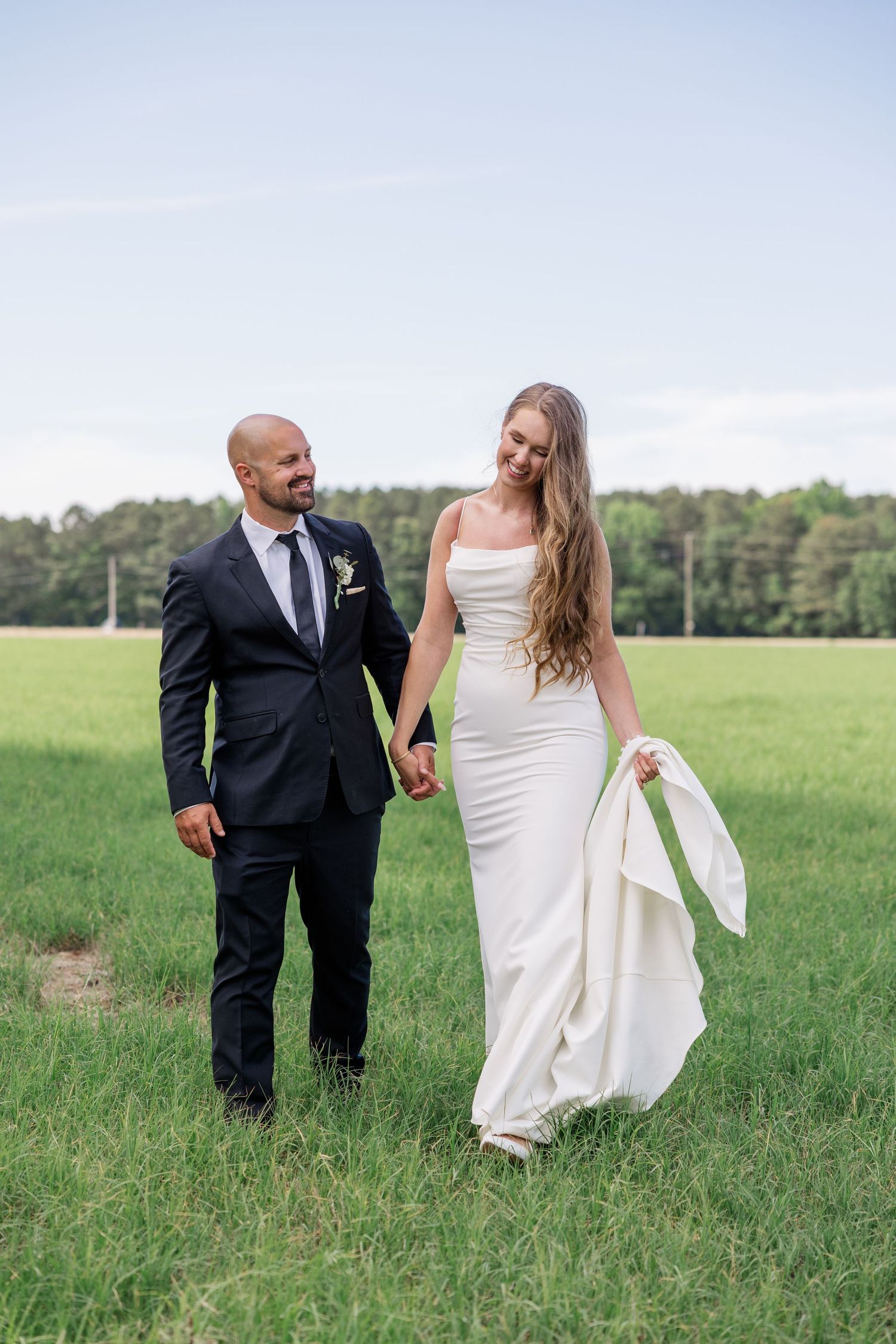 Couple takes romantic photos together in an open green field.