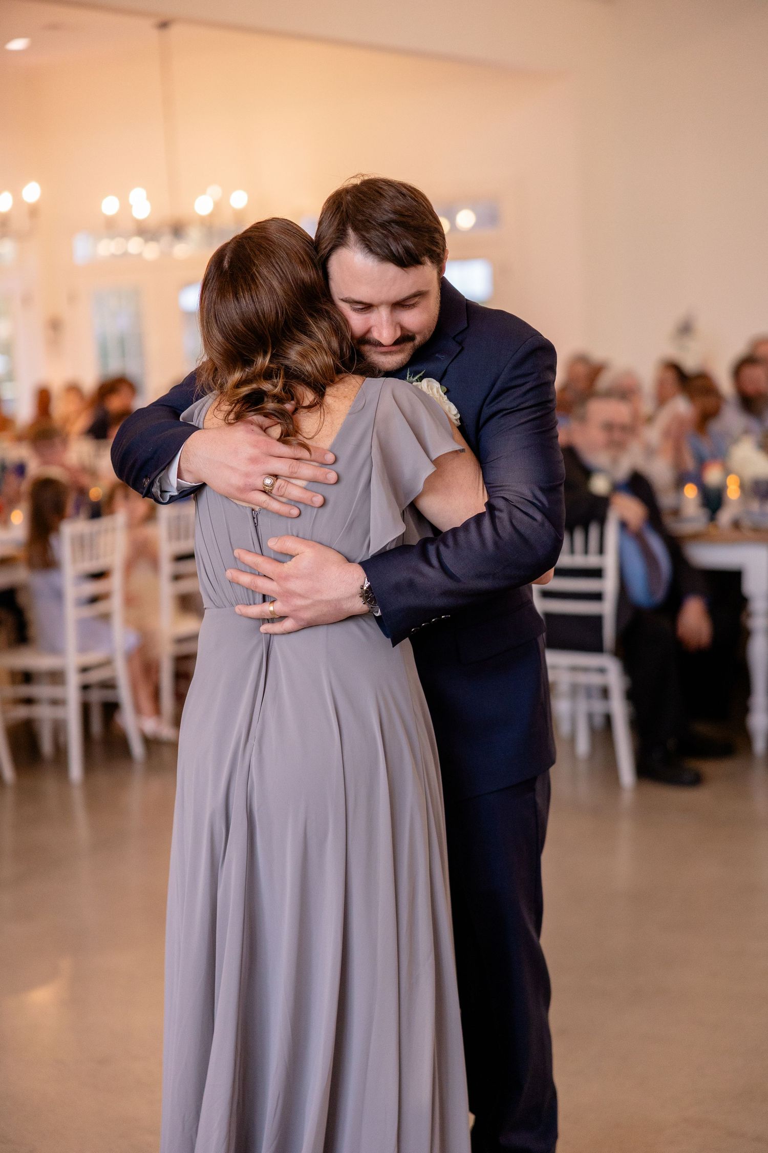 Touching dance moment between two figures in a bright reception hall.