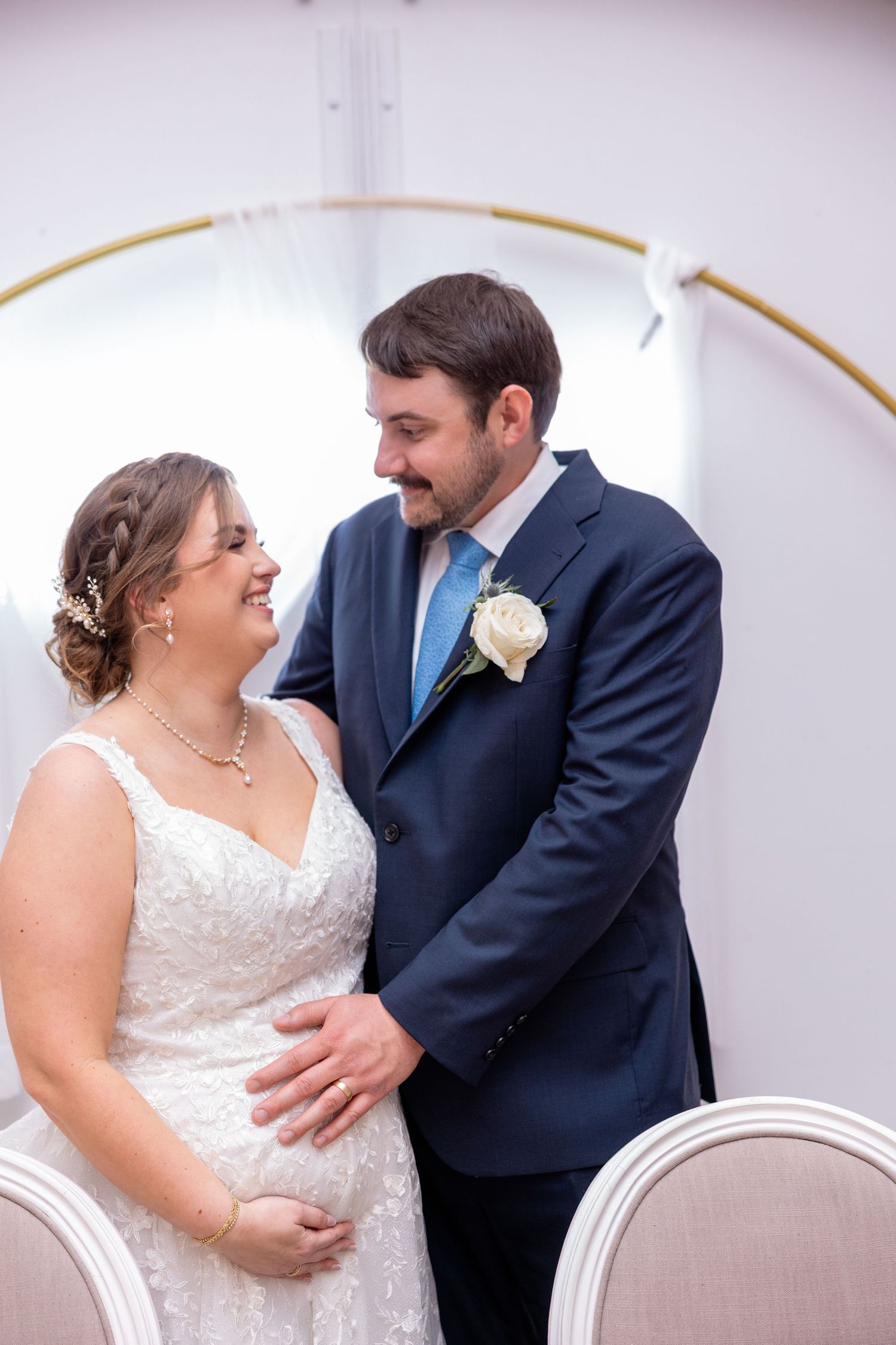 Couple shares intimate moment under gold archway during wedding celebration.