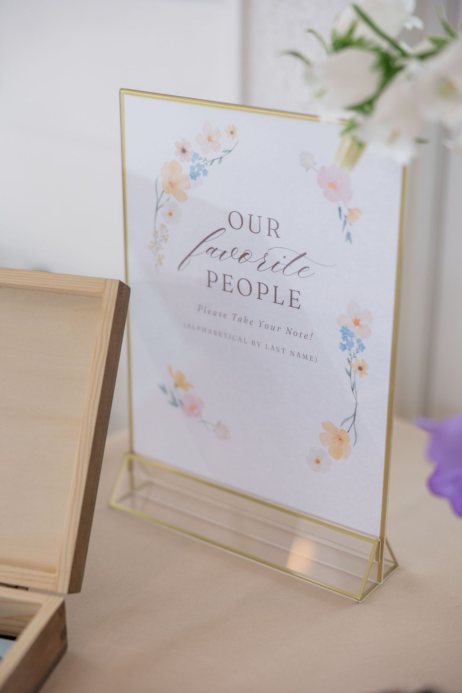 Wedding signage in a gold frame reading 'Our Favorite People' with delicate floral watercolor details.