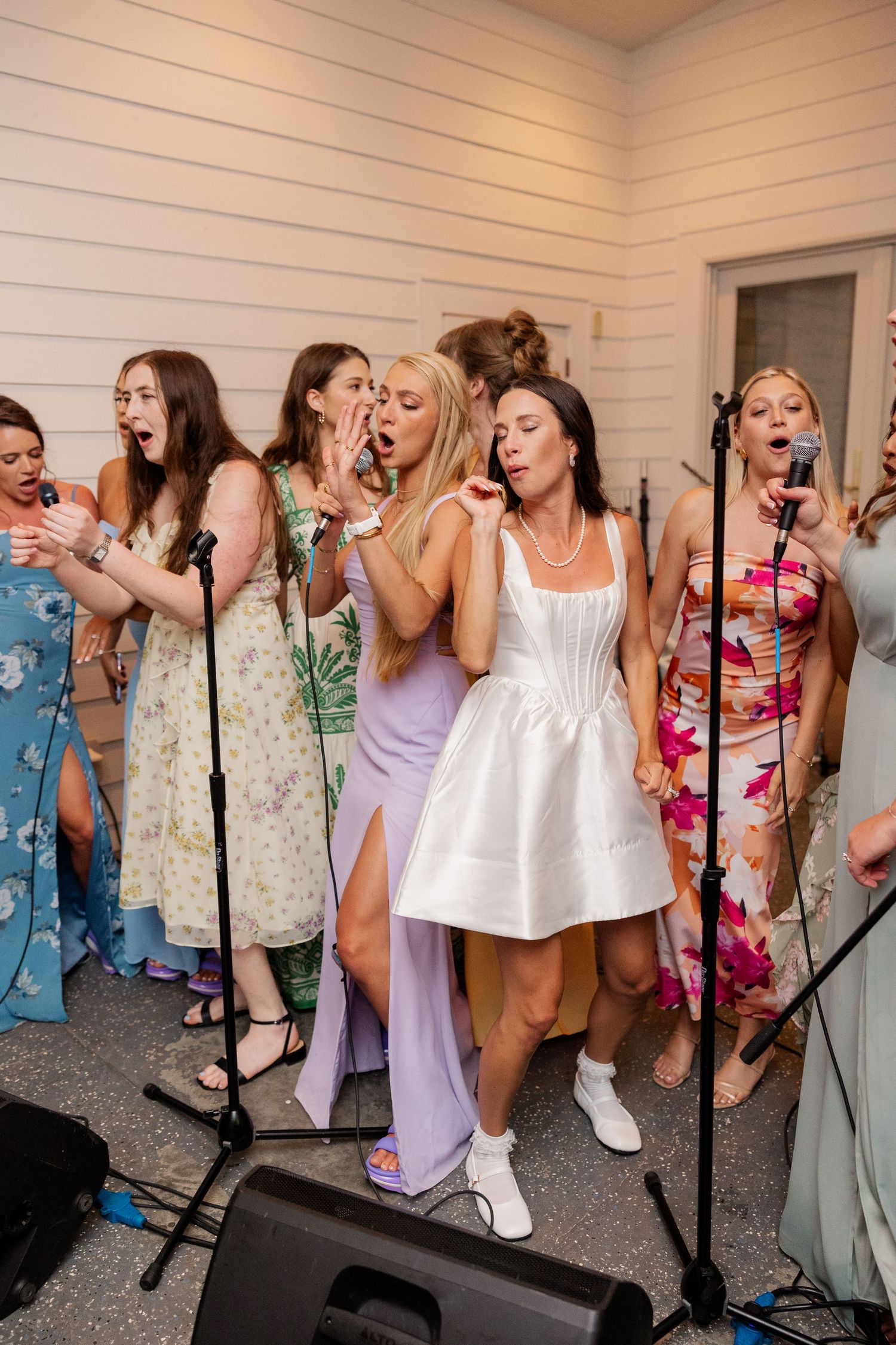 Group celebrating at wedding reception in colorful summer dresses and casual attire.