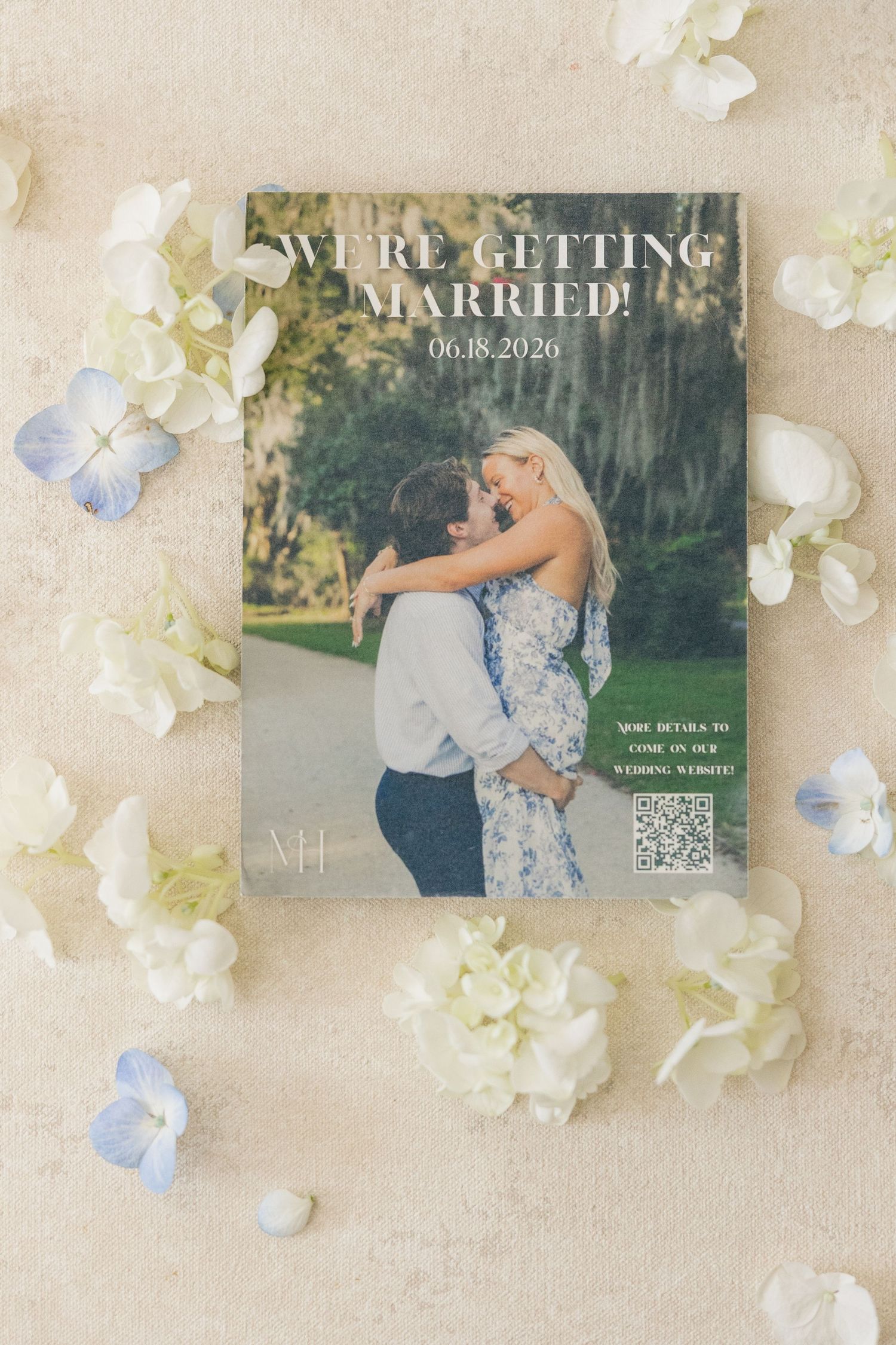 Save the date card reading We're Getting Married surrounded by white hydrangeas.
