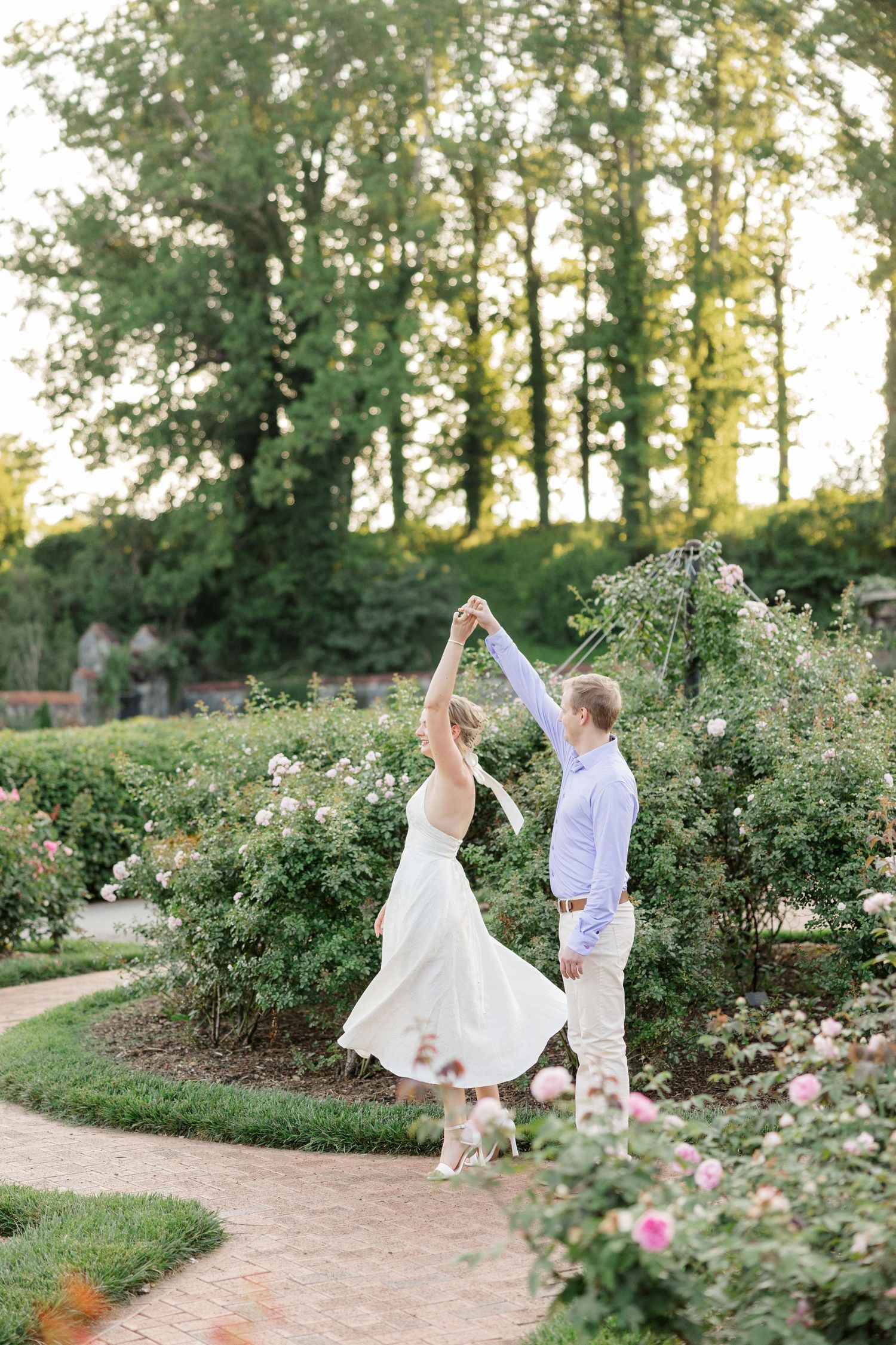 A joyful dancing sequence in a lush garden path surrounded by greenery and flowers at sunset.