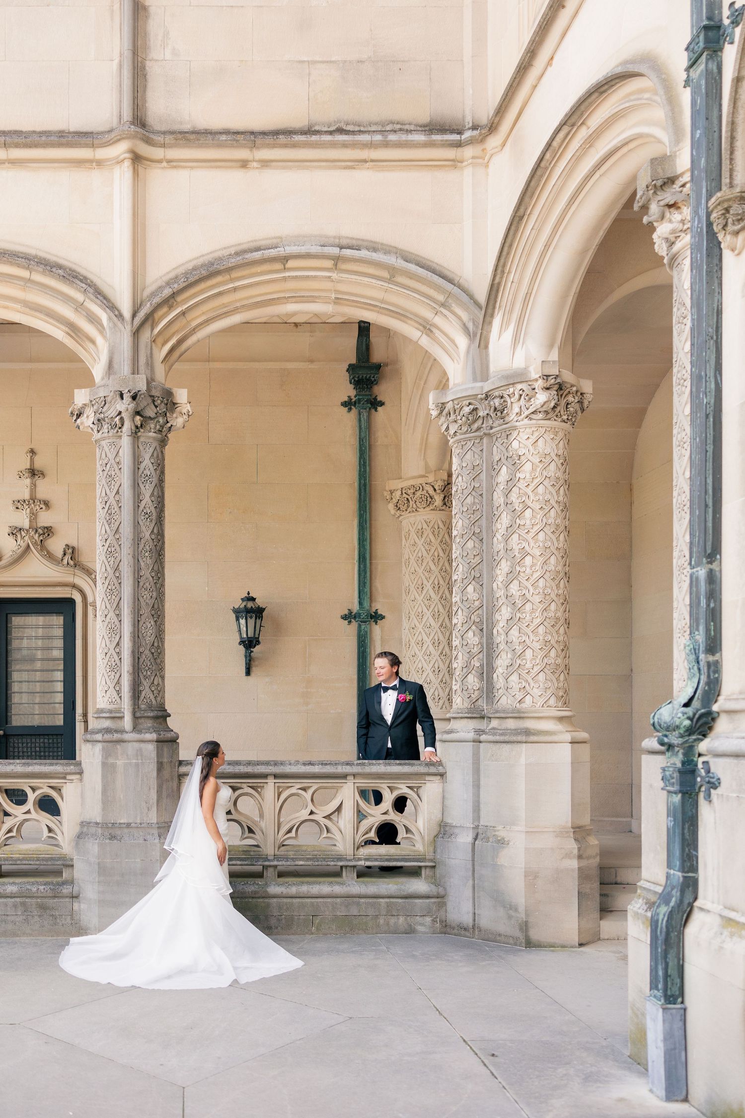 Bride and groom share romantic first look under ornate stone arches at venue.