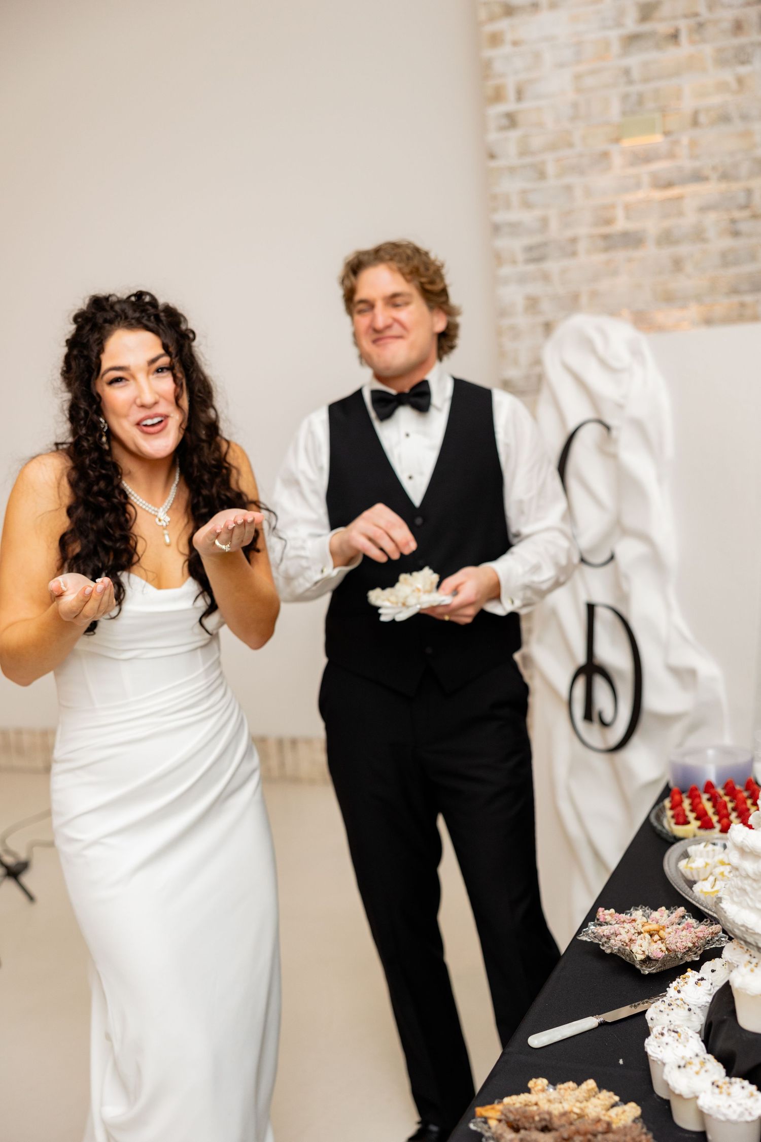 A joyful wedding celebration moment at the dessert table in an elegant reception venue.