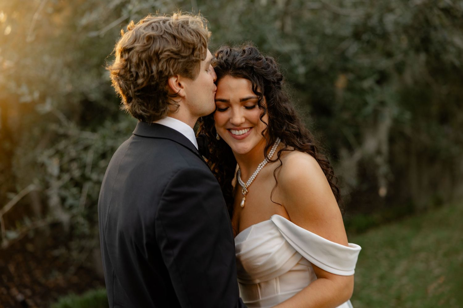 Intimate moment between newlyweds during sunset outdoor wedding portraits.