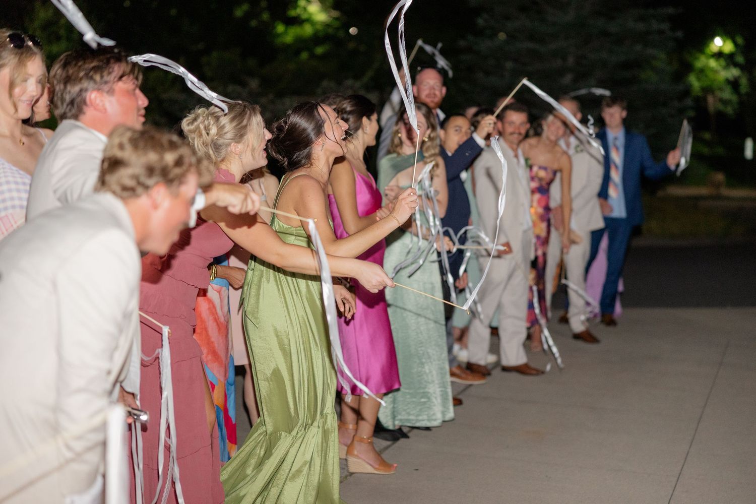 Wedding guests form an archway with raised sparklers at night creating a magical tunnel of light.