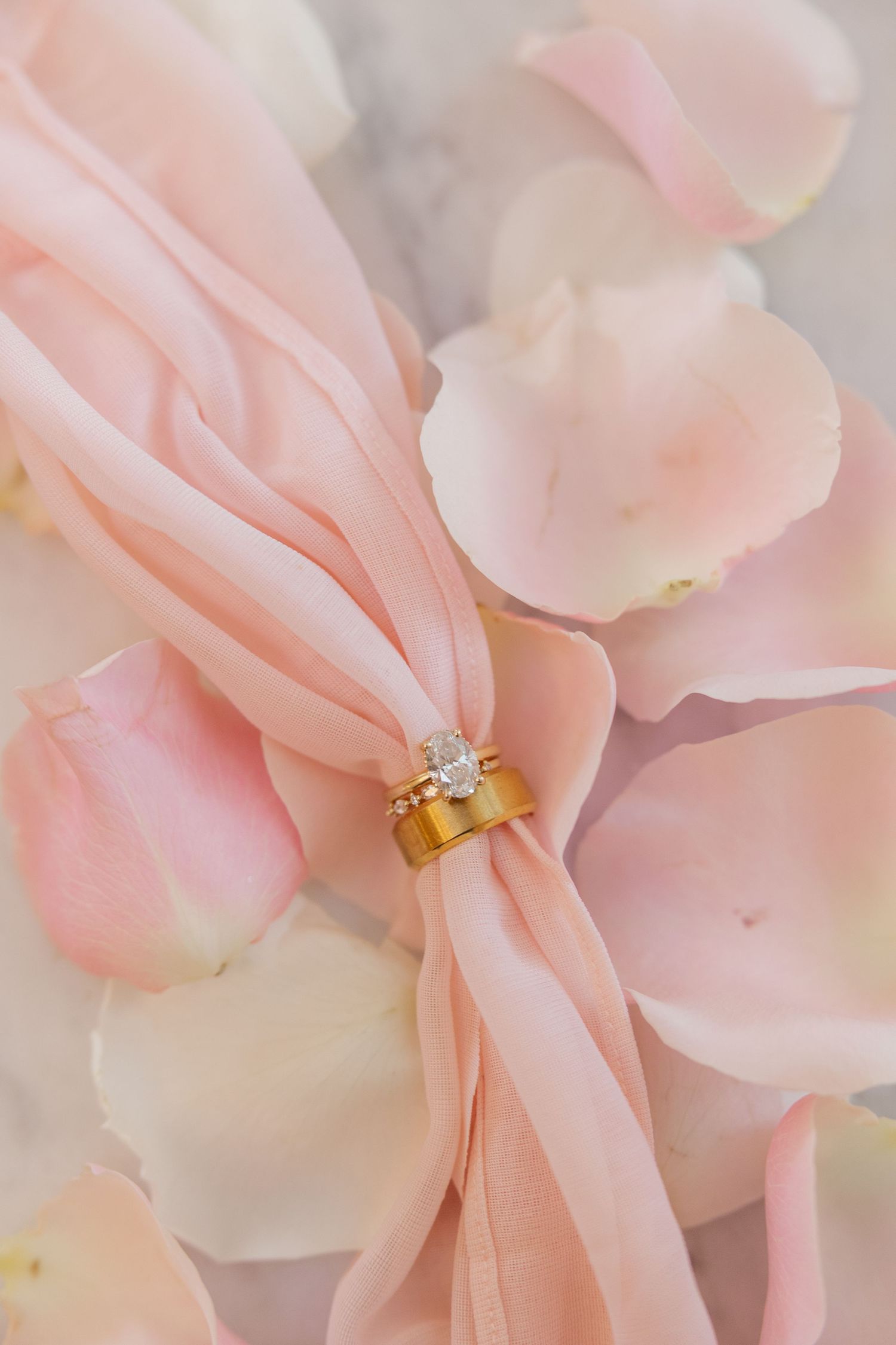 Delicate pink rose petals arranged with a diamond engagement ring nestled among them.