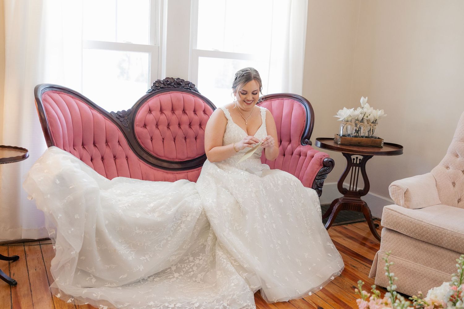White wedding gown with full skirt photographed in an elegant room with pink vintage furniture.