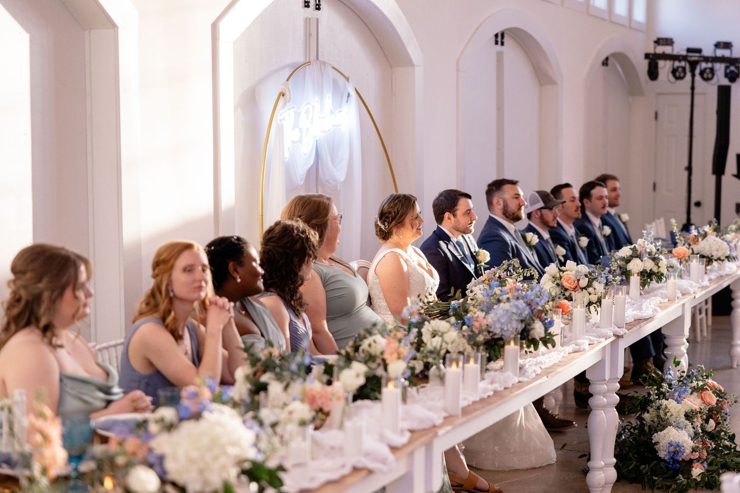 Elegant wedding reception hall with long tables and white decor under arched ceilings.