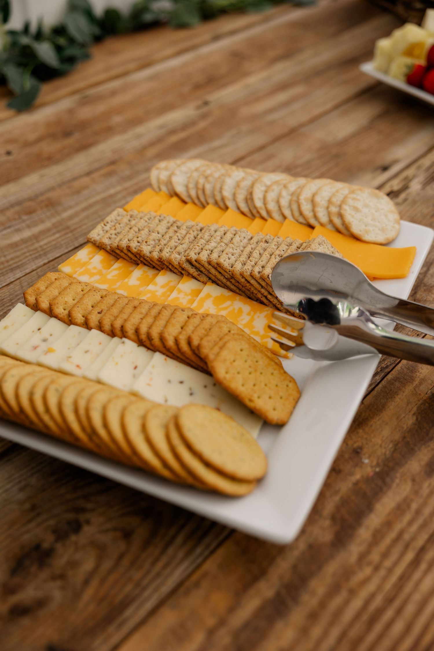 Assorted crackers and bread slices arranged on a white serving platter on a rustic wooden table.