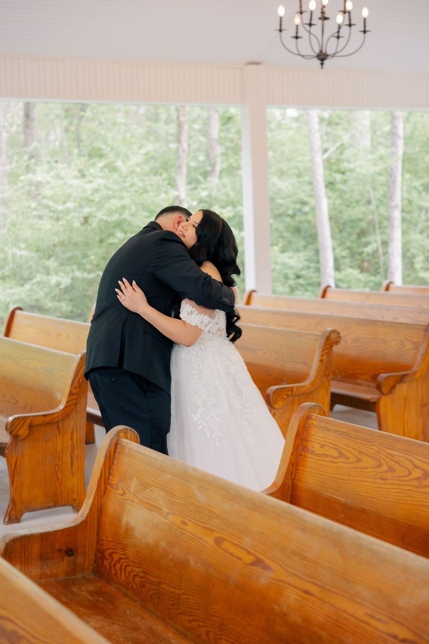 A touching moment between newlyweds in a rustic wooden church pew setting.