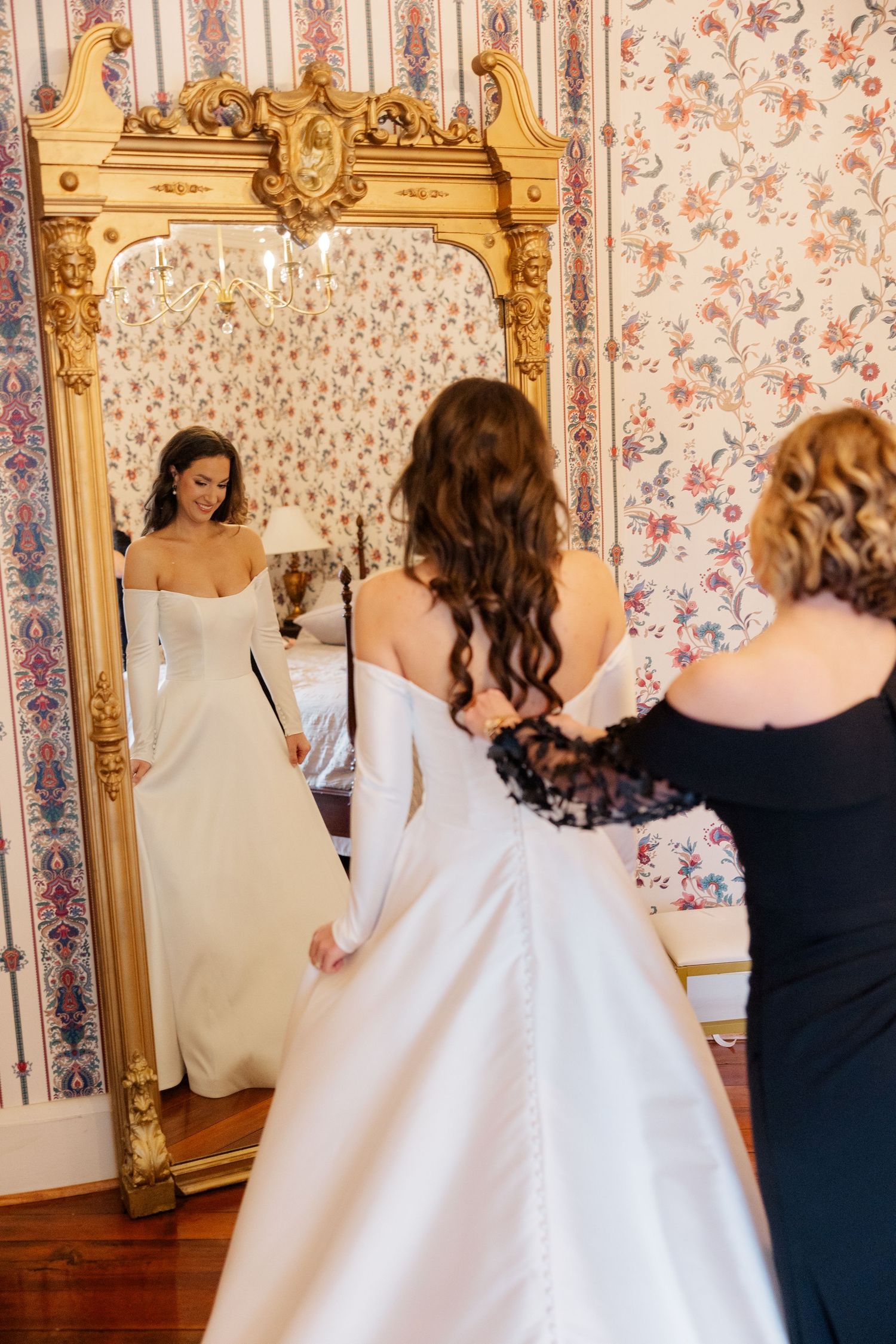 A series of people getting ready in a vintage-styled room with ornate gold mirrors and floral wallpaper.