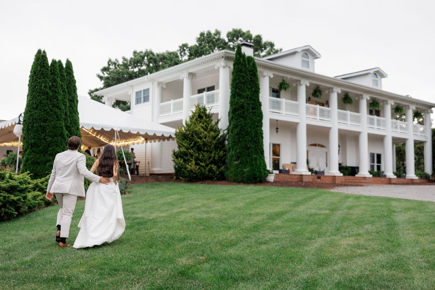 Elegant white colonial-style mansion with tall columns and manicured lawn serving as a wedding venue.