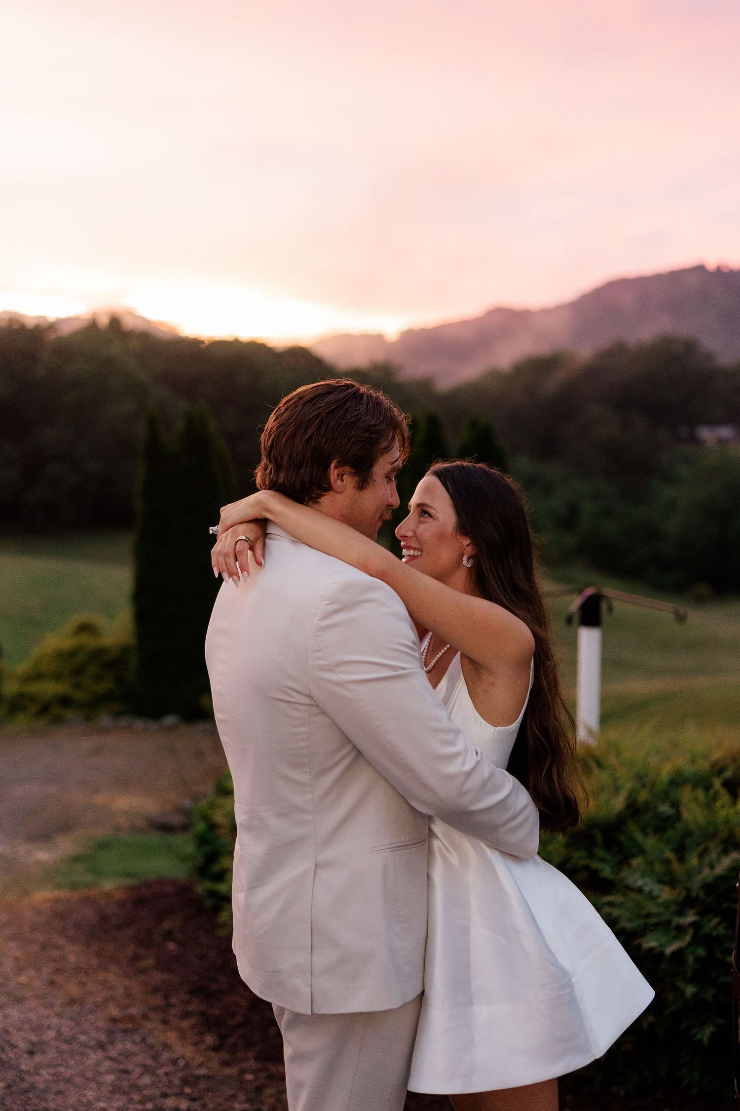 Couple embracing during sunset with mountains in the background at their outdoor wedding.