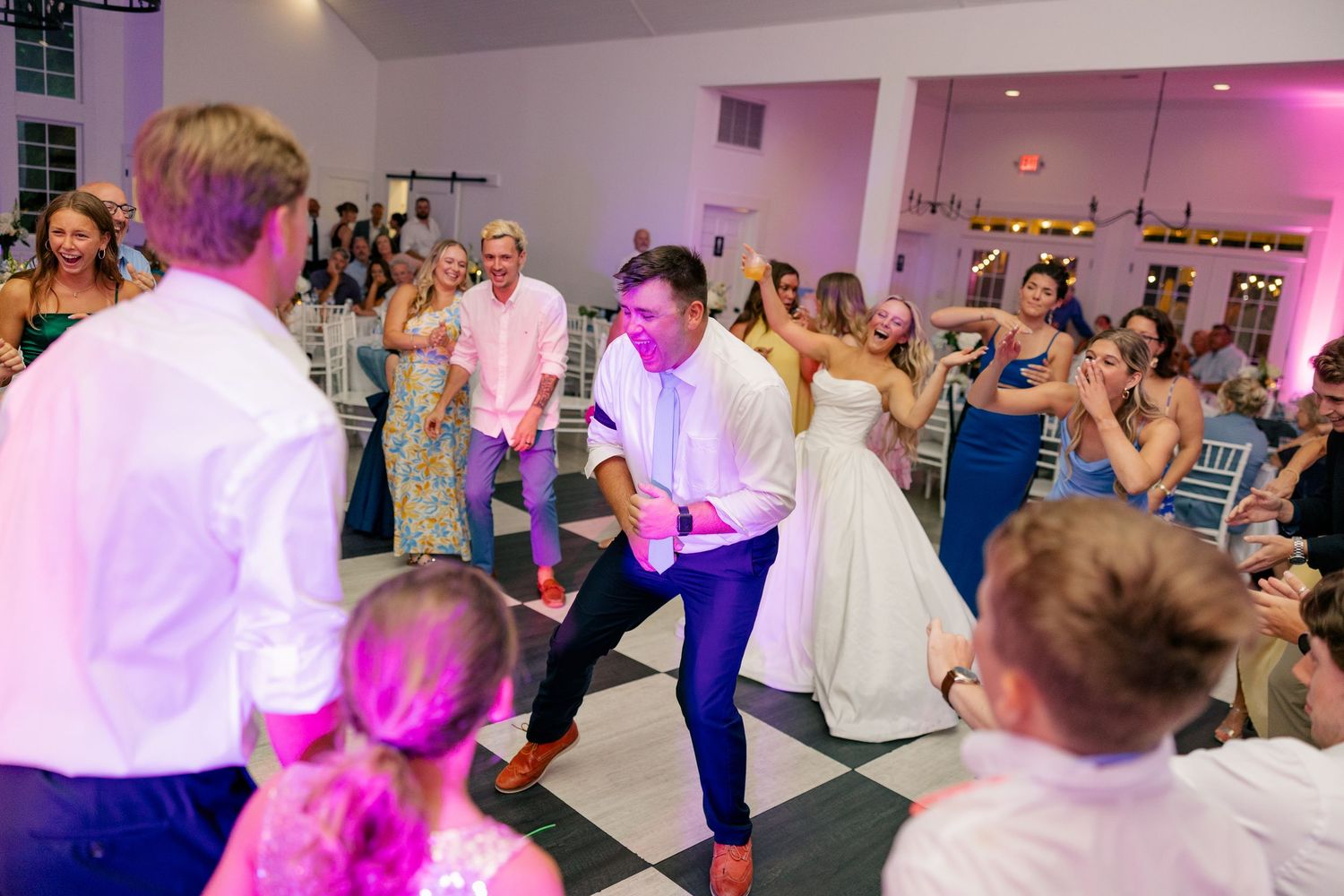 Energetic wedding reception dance floor with guests celebrating alongside the bride and groom.