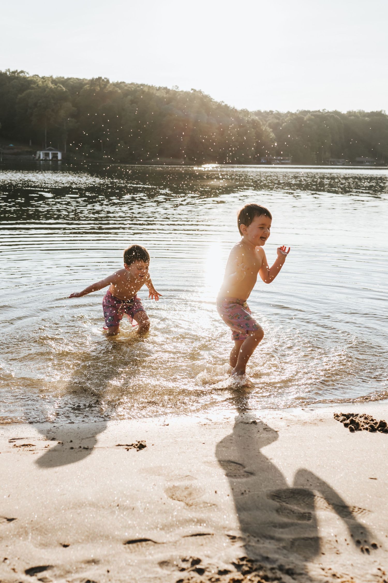 two brothers are playing in the water splashing and laughing on a warm summer day