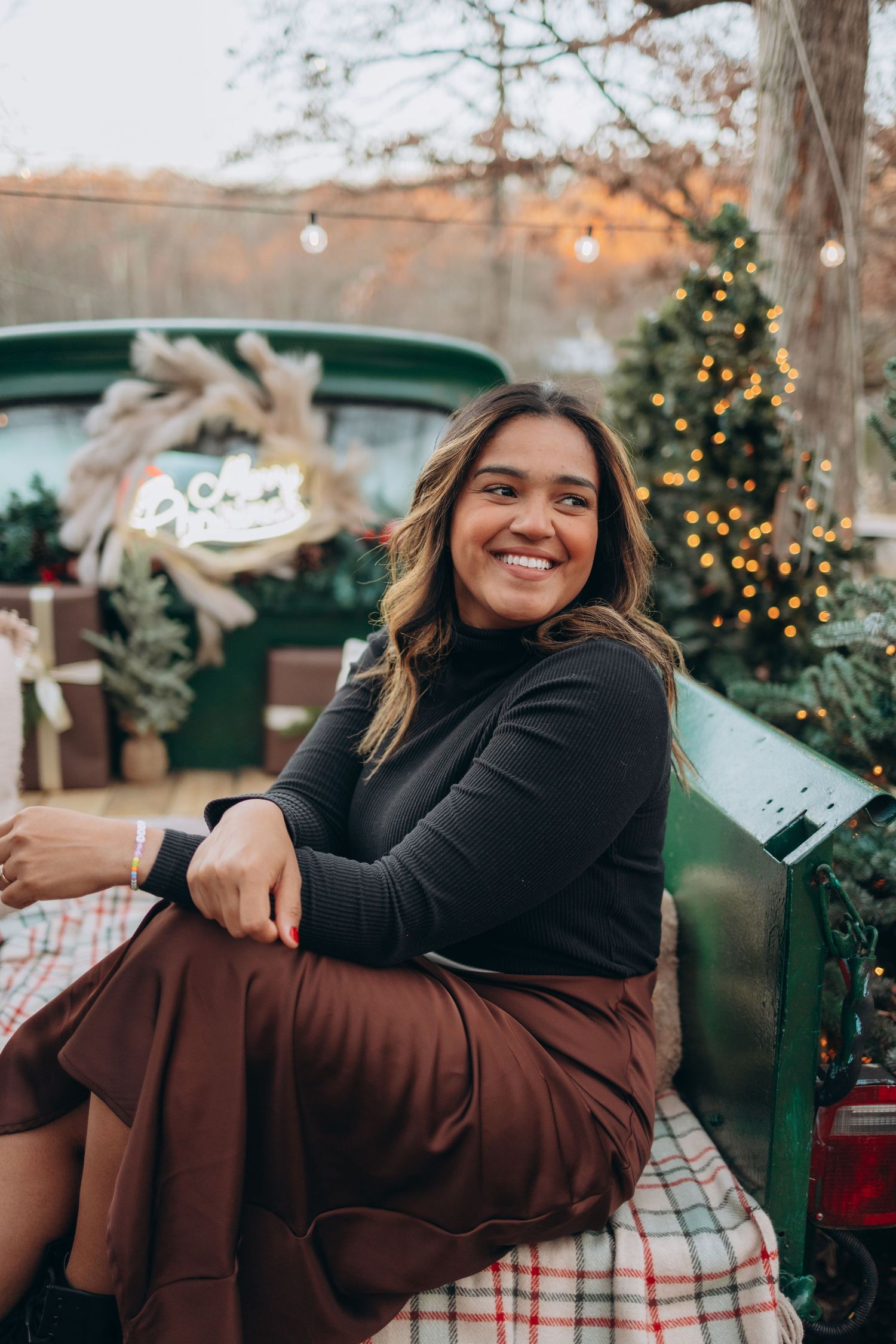 A casual portrait on a decorated holiday bench with festive lights in the background.
