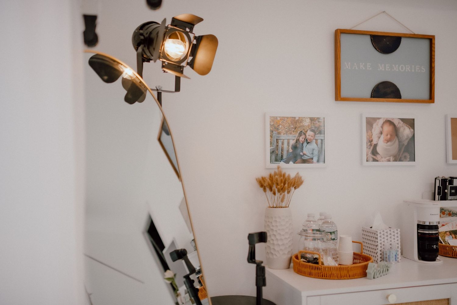 Photography studio setup with lighting equipment and framed artwork on white walls.
