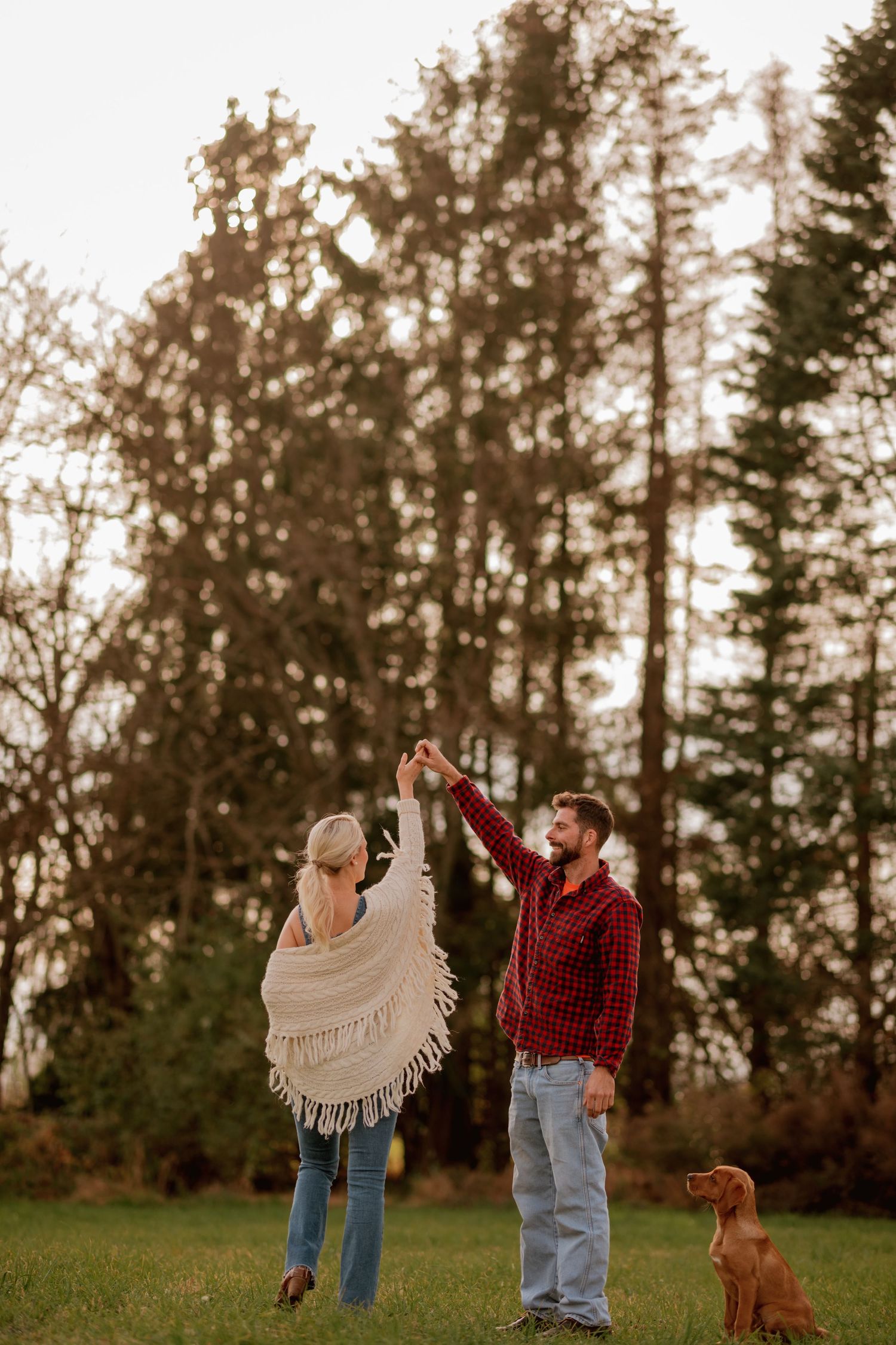 A couple dancing outdoors at sunset with their dog watching nearby.