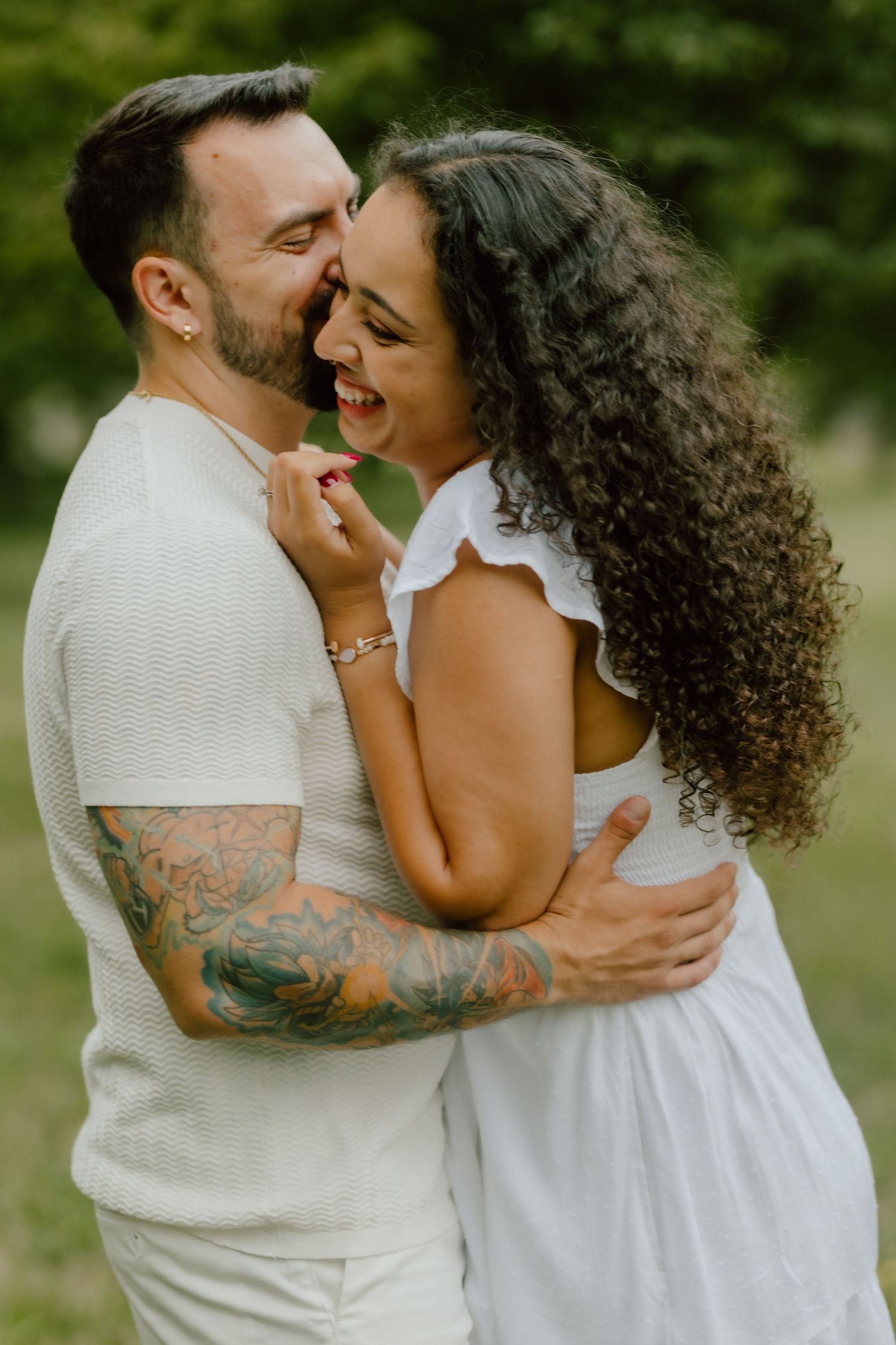 A romantic outdoor photoshoot with a couple in white embracing and sharing an intimate moment.